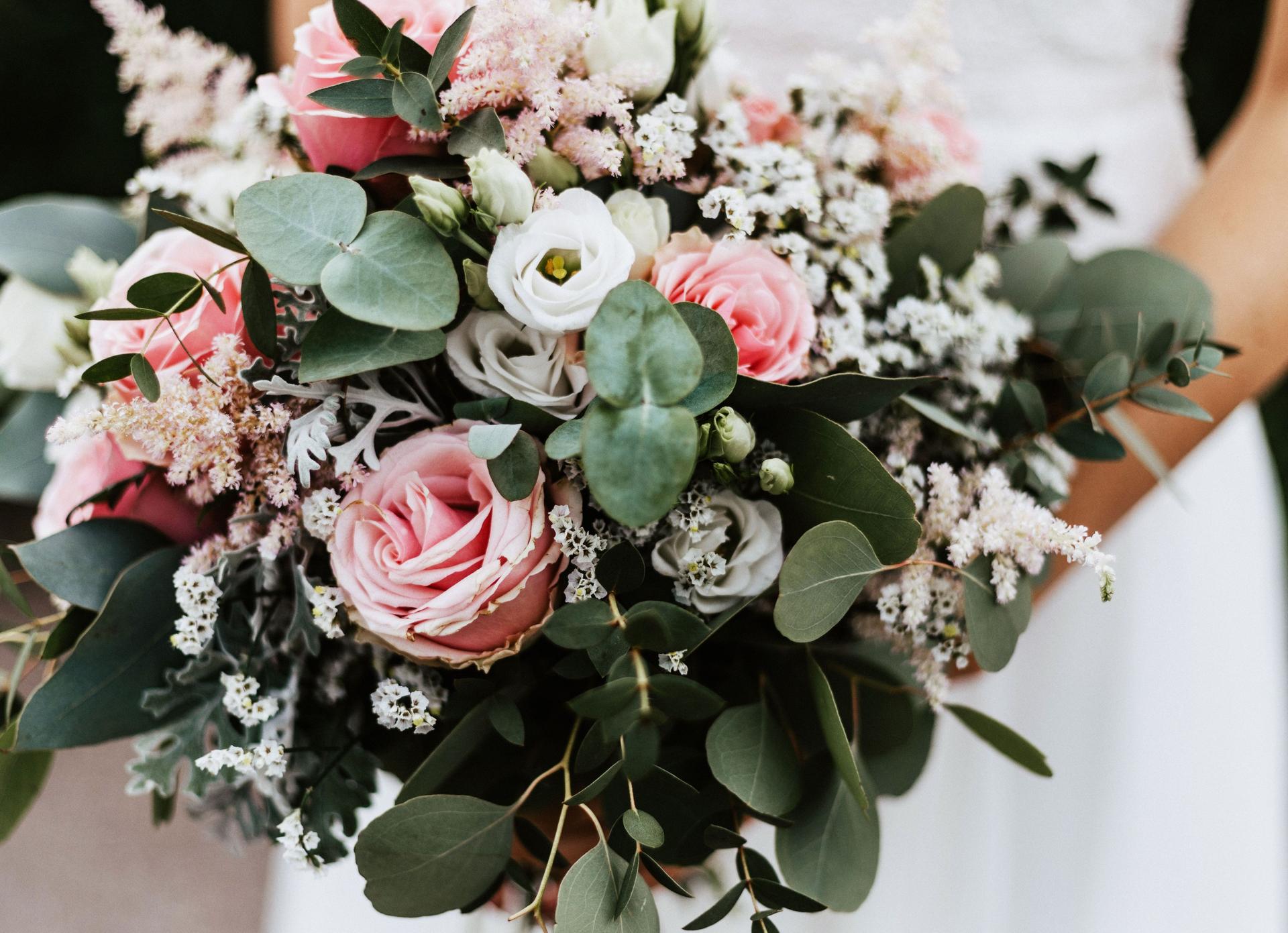 Braut hält ihren Brautstrauß mit rosa Rosen und Eukalyptus