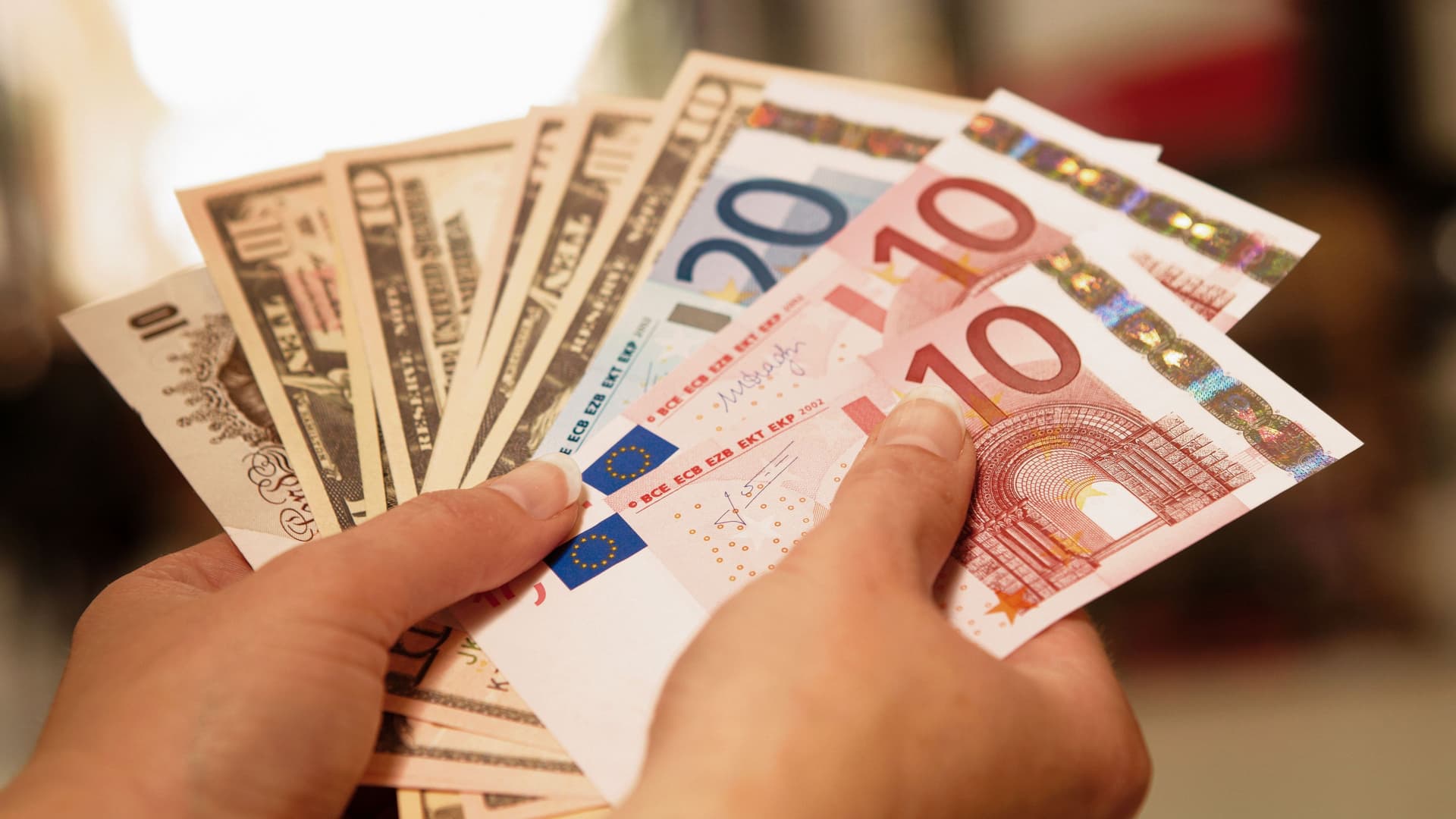 Zwei Hände halten Fächer aus Banknoten verschiedener Währungen