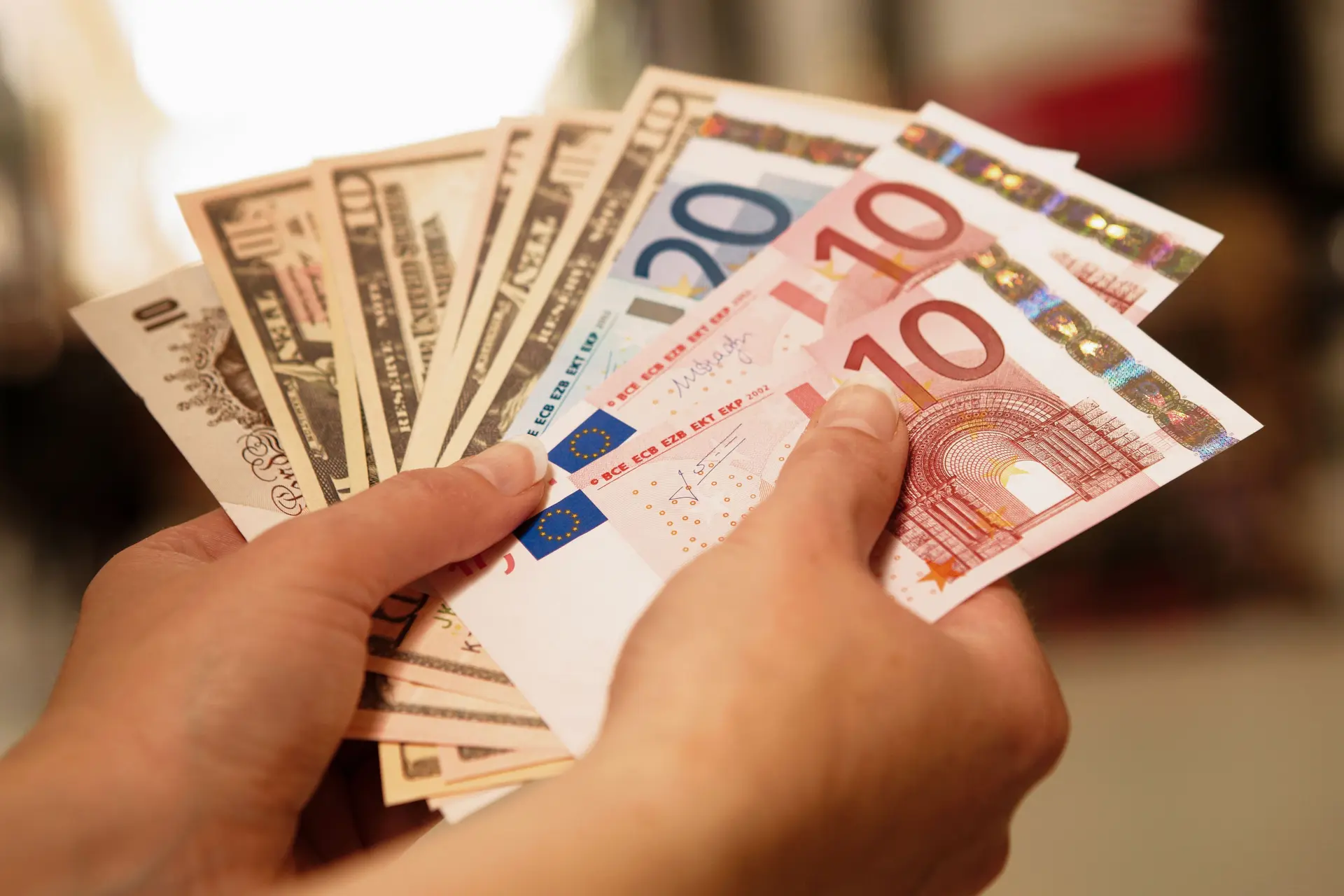 Zwei Hände halten Fächer aus Banknoten verschiedener Währungen