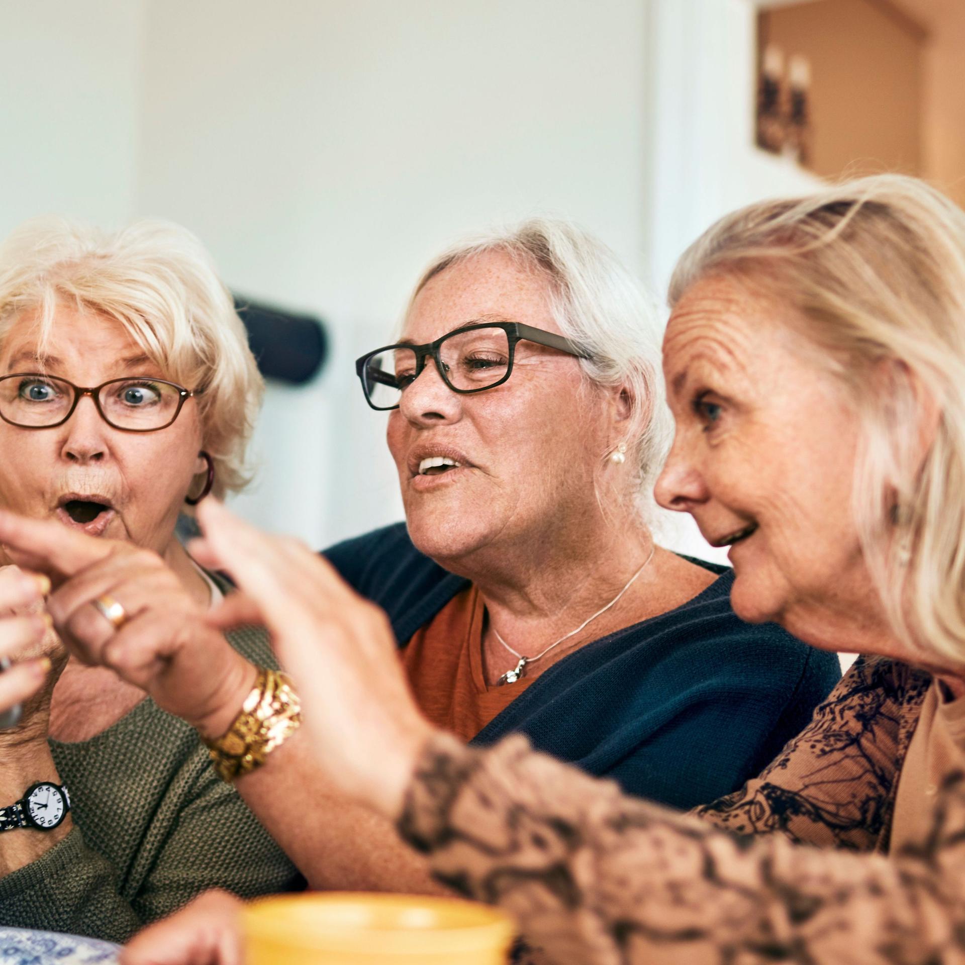 Drei ältere Damen beim Kaffee Kuchen amüsieren sich mit Handy