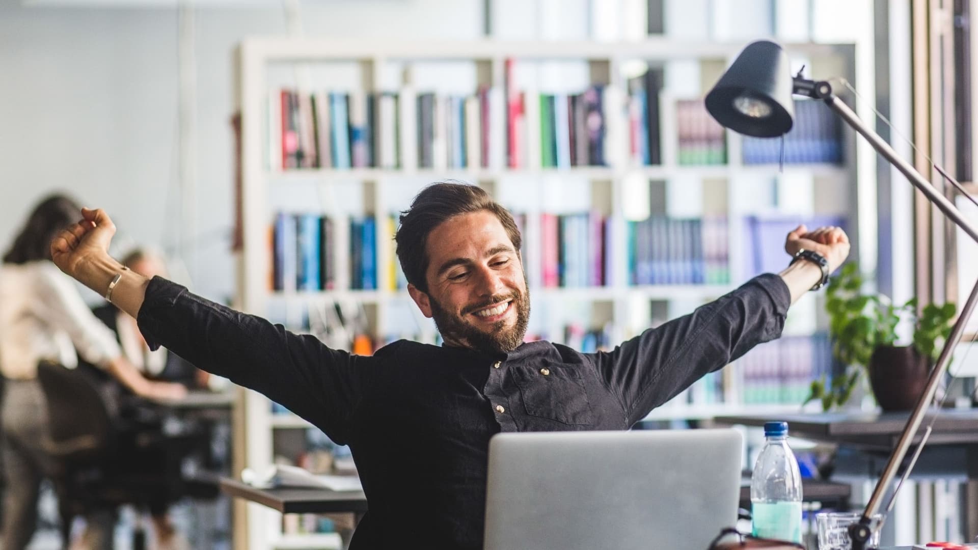 Ein junger Mann lehnt sich entspannt im BVüro zurück. Er streckt die Arme aus.