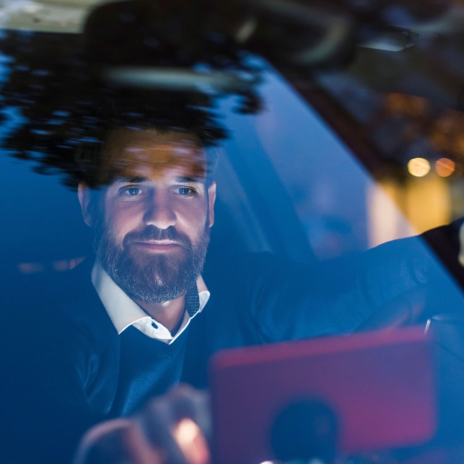 Ein Mann sitzt in seinem Auto und tippt auf sein Smartphone