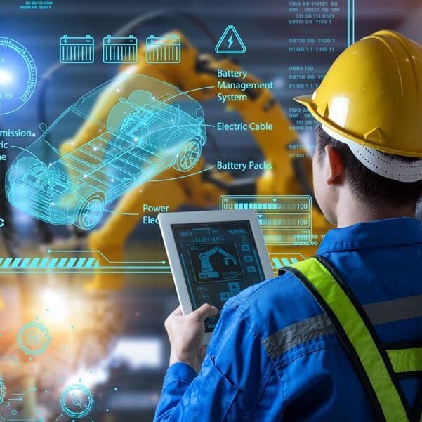 Ein Mann mit Schutzhelm steht vor einer Glswand mit Projektionen. Im Hintergrund sieht man eine Produktionsstraße mit Robotern.