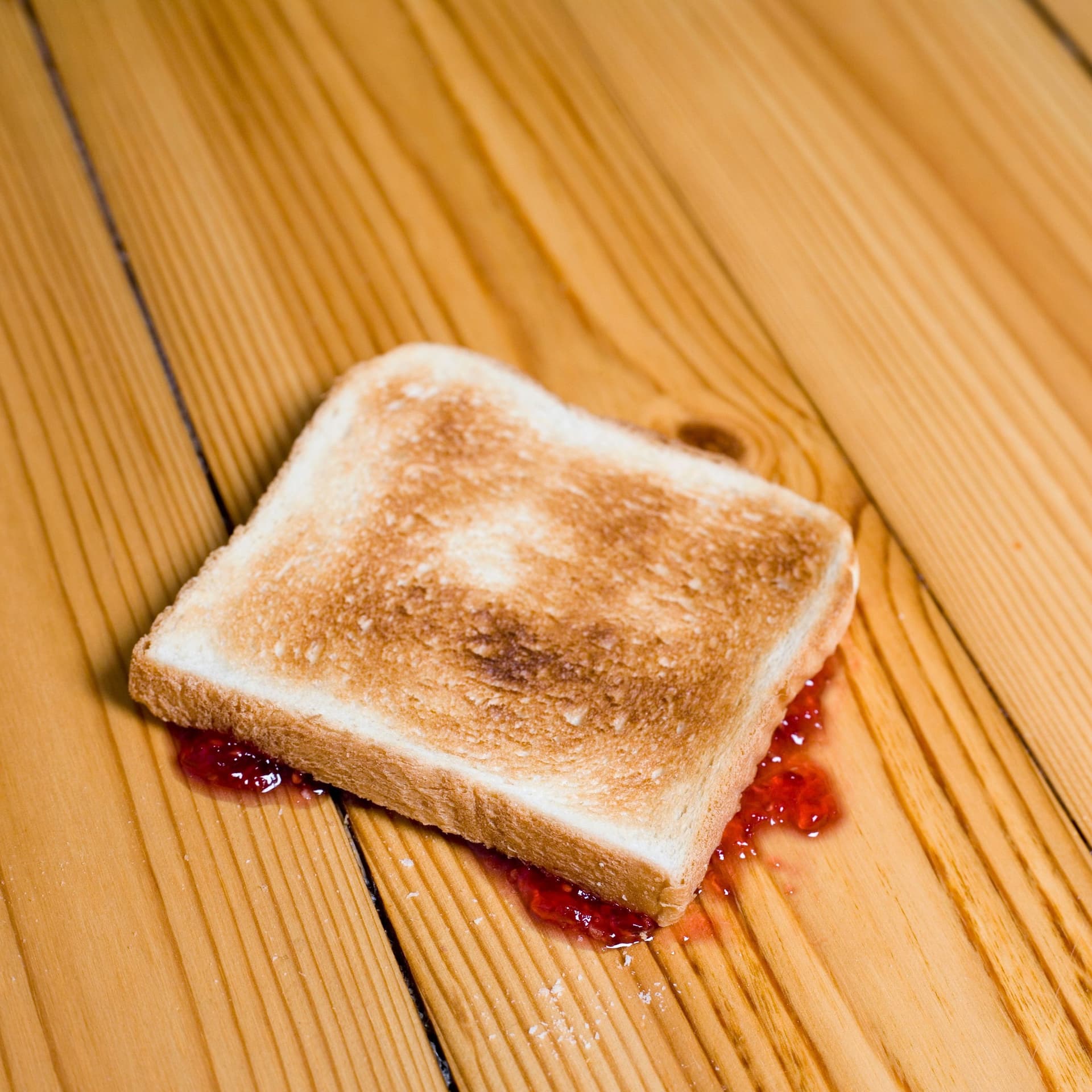Ein Toastbrot liegt auf der Marmeladenseite auf dem Boden.