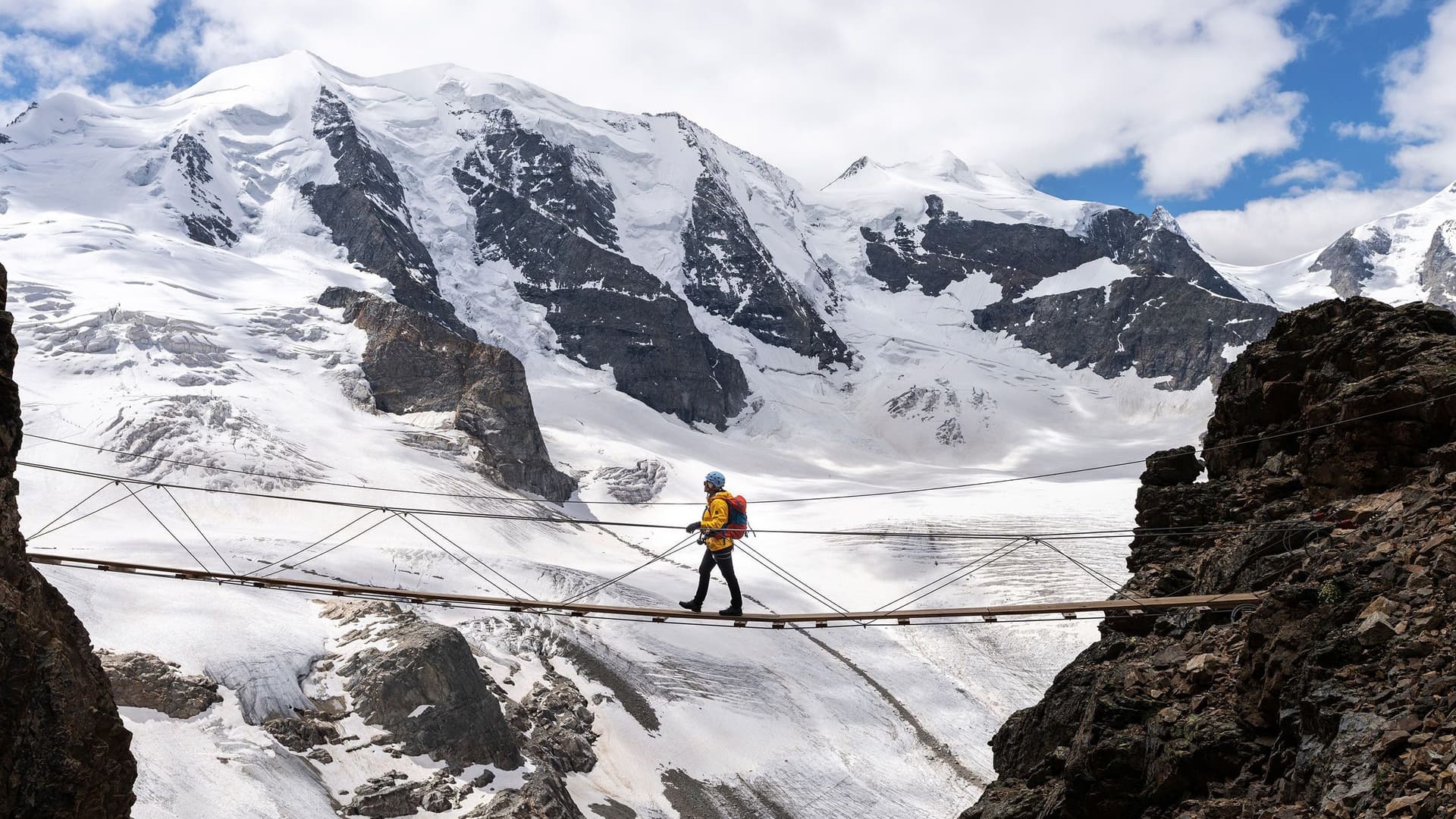 Ein Wanderer auf einer Hängebrücke in den Alpen.