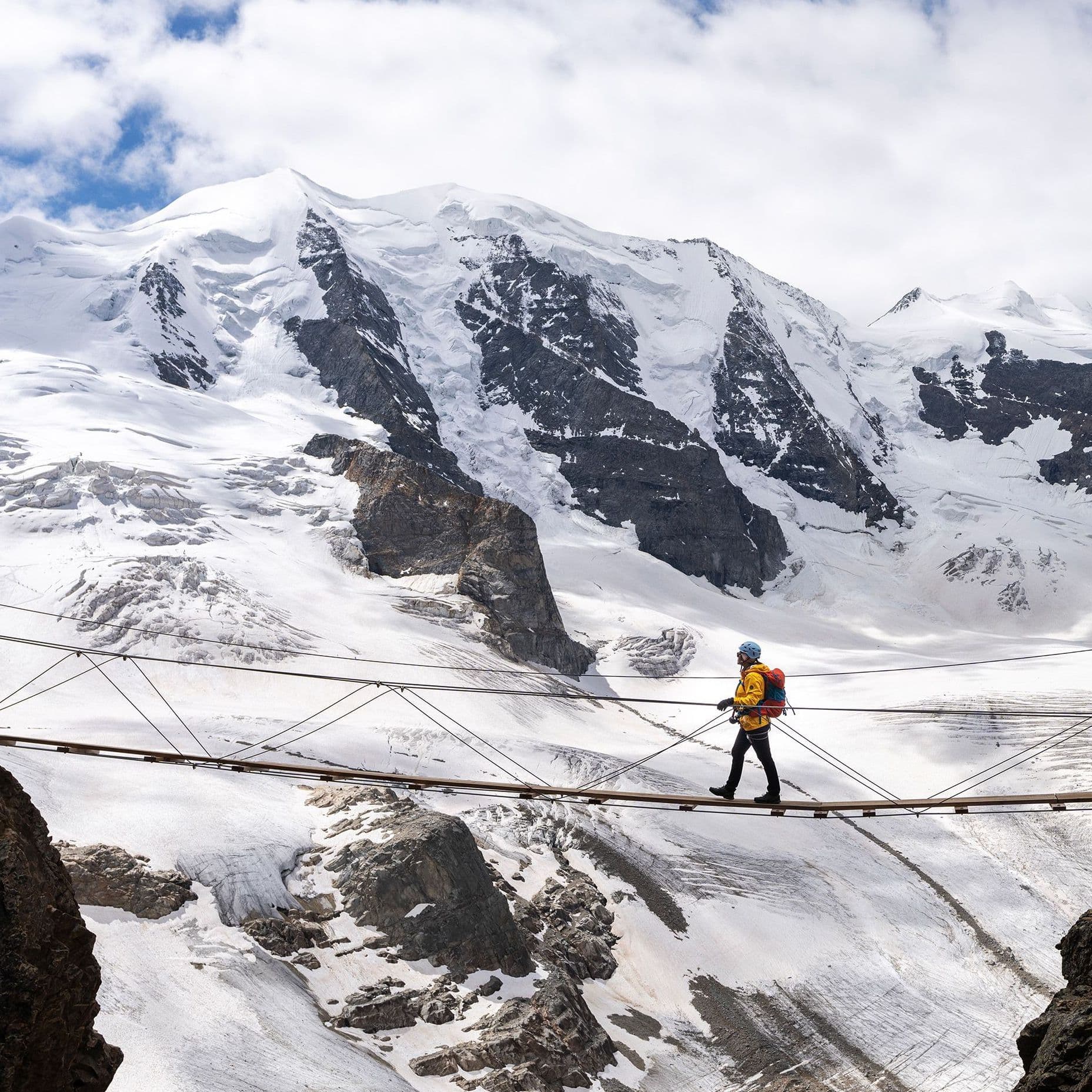 Ein Wanderer auf einer Hängebrücke in den Alpen.