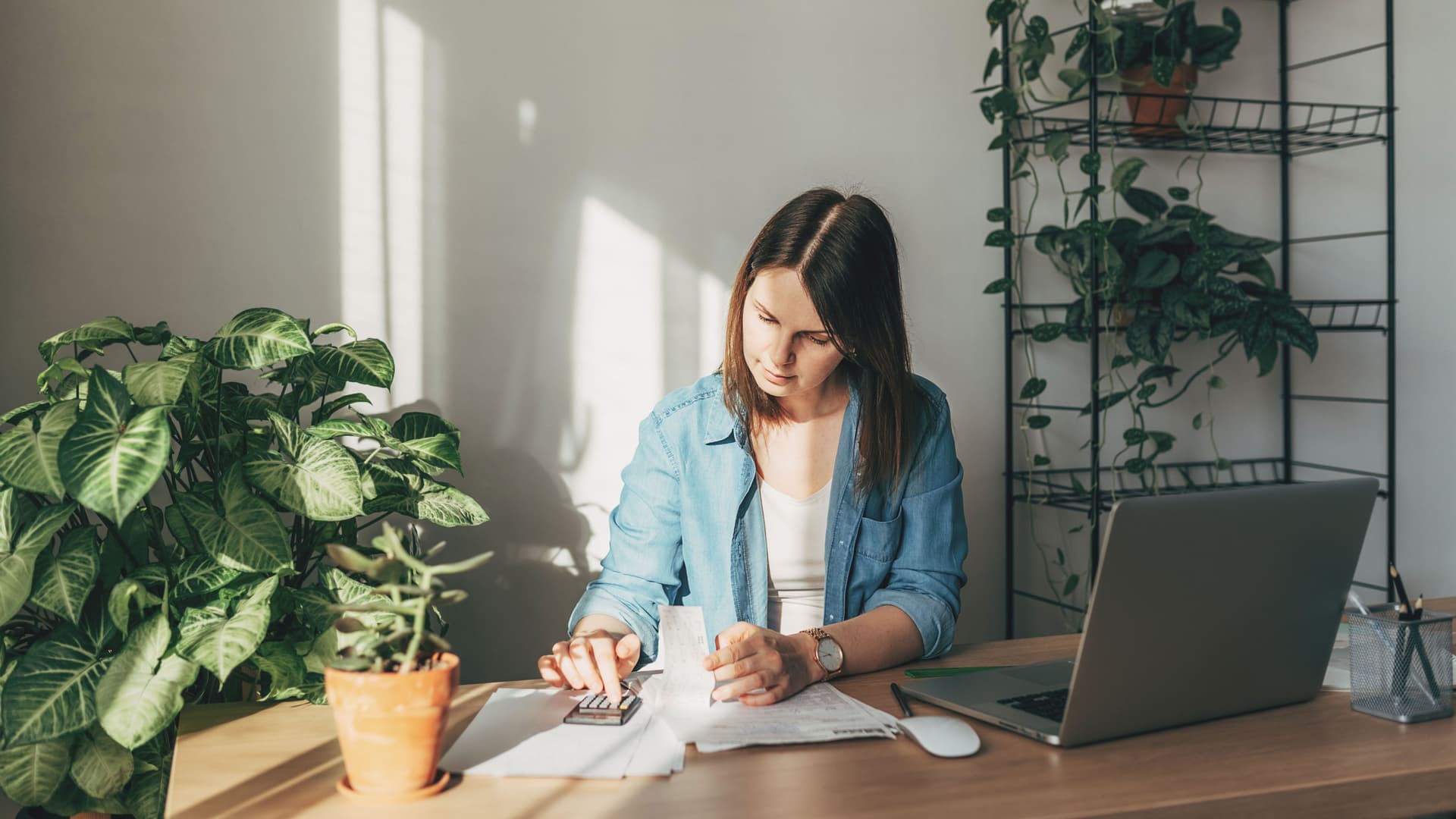 Eine junge Frau macht an einem Schreibtisch zu Hause Buchhaltung