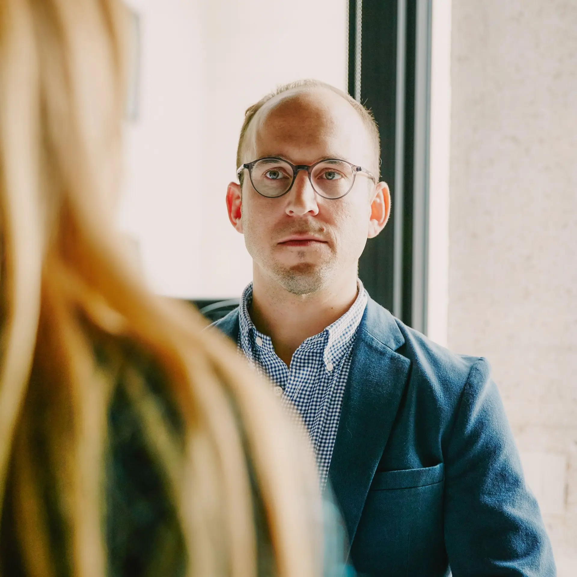 Ein Mann sitzt mit zwei Frauen in einem Büro. Von den beiden Frauen sieht man nur einen Teil.