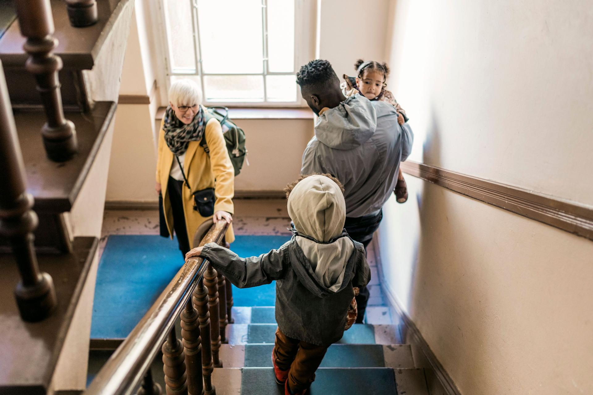 Eine Familie, die gemeinsam eine Treppe hinuntergeht, um das Haus zu verlassen.