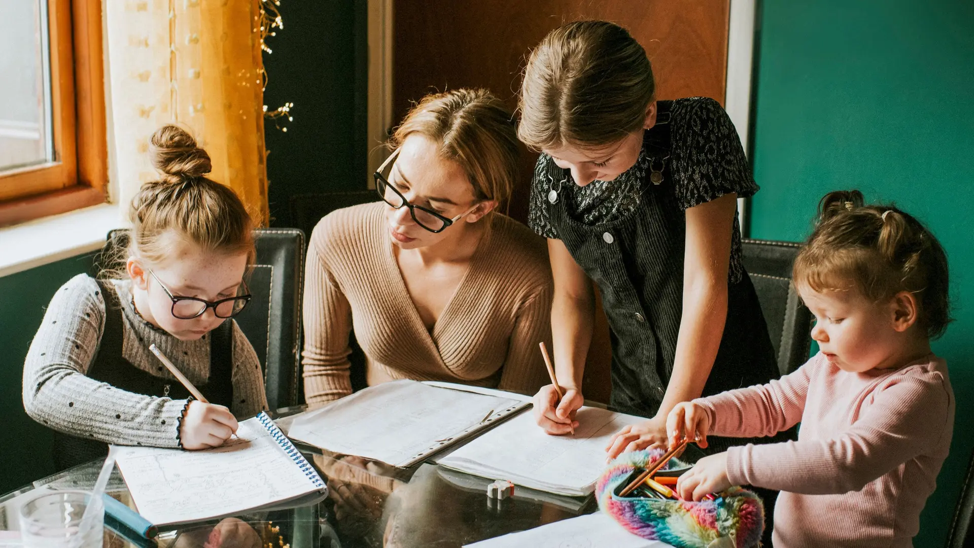 Mutter macht mit drei Töchtern Hausaufgaben