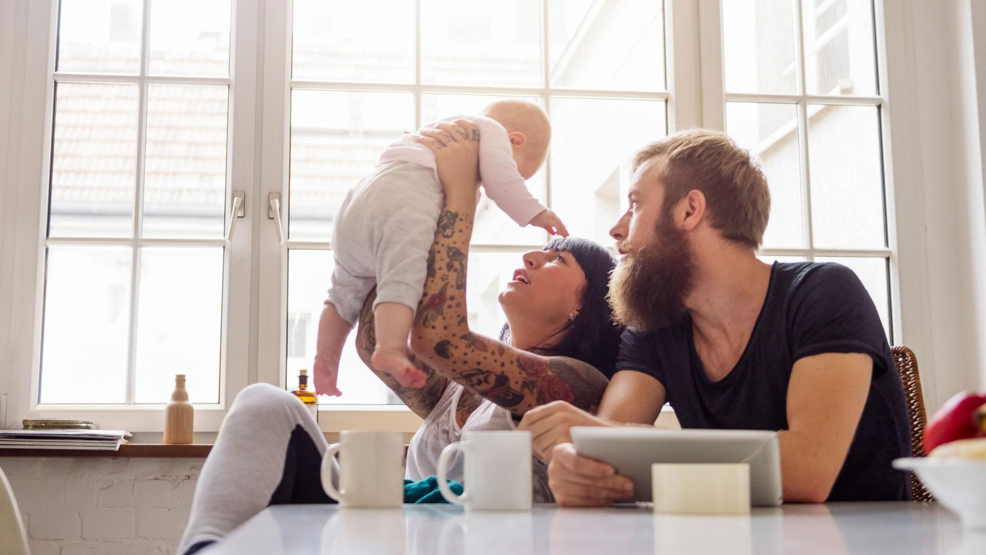 Junge Familie mit Säugling am Küchentisch
