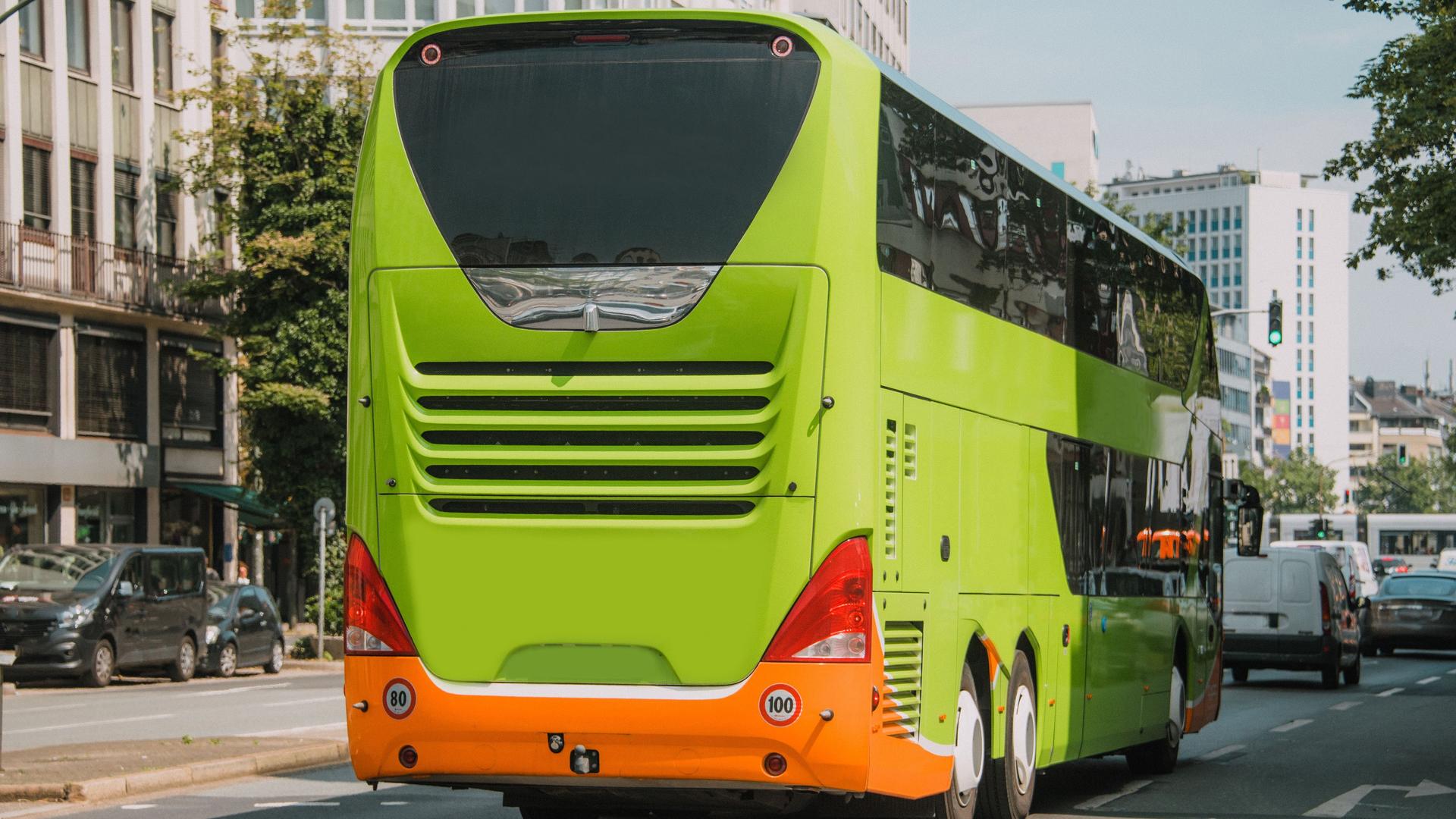 Ein grüner Bus fährt durch eine Innenstadt.