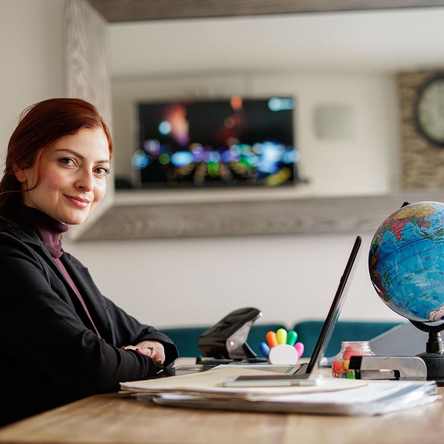Frau am Tisch mit Laptop und Globus