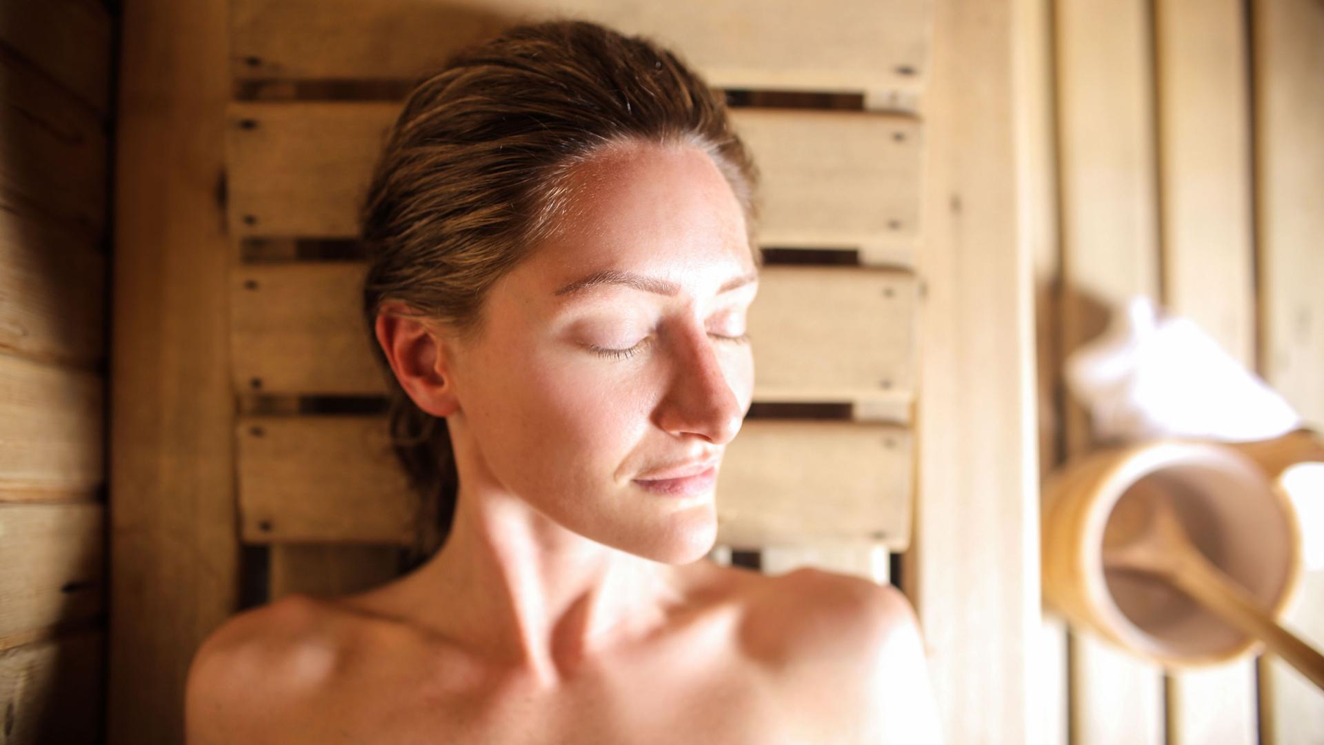 Frau mit geschlossenen Augen in einer Sauna.