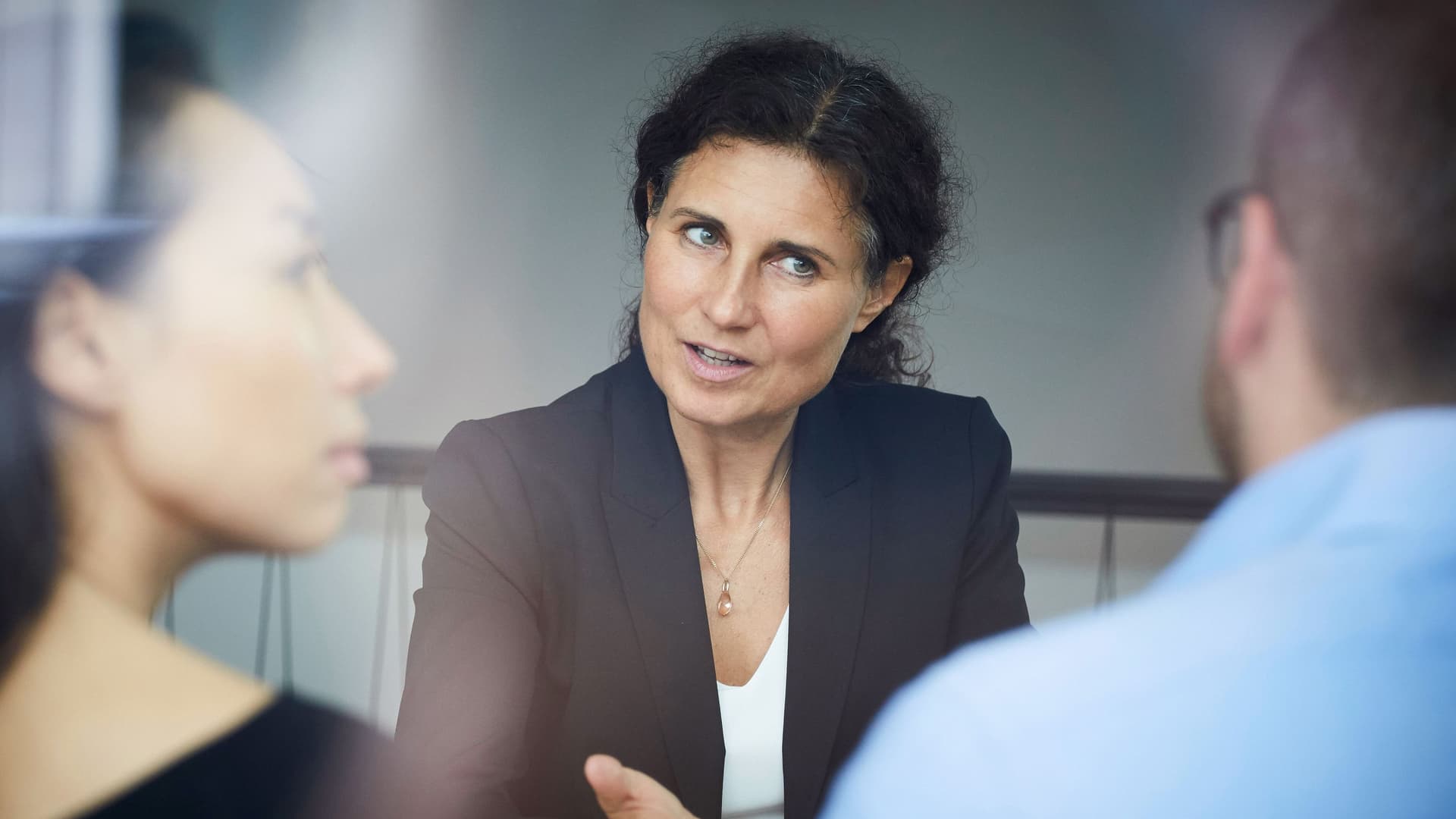 Business Frau diskutiert mit zwei Personen, die ihr gegenübersitzen
