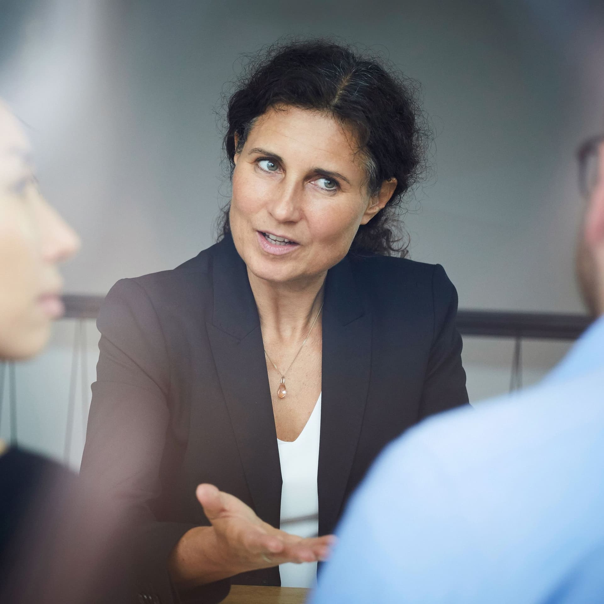 Business Frau diskutiert mit zwei Personen, die ihr gegenübersitzen