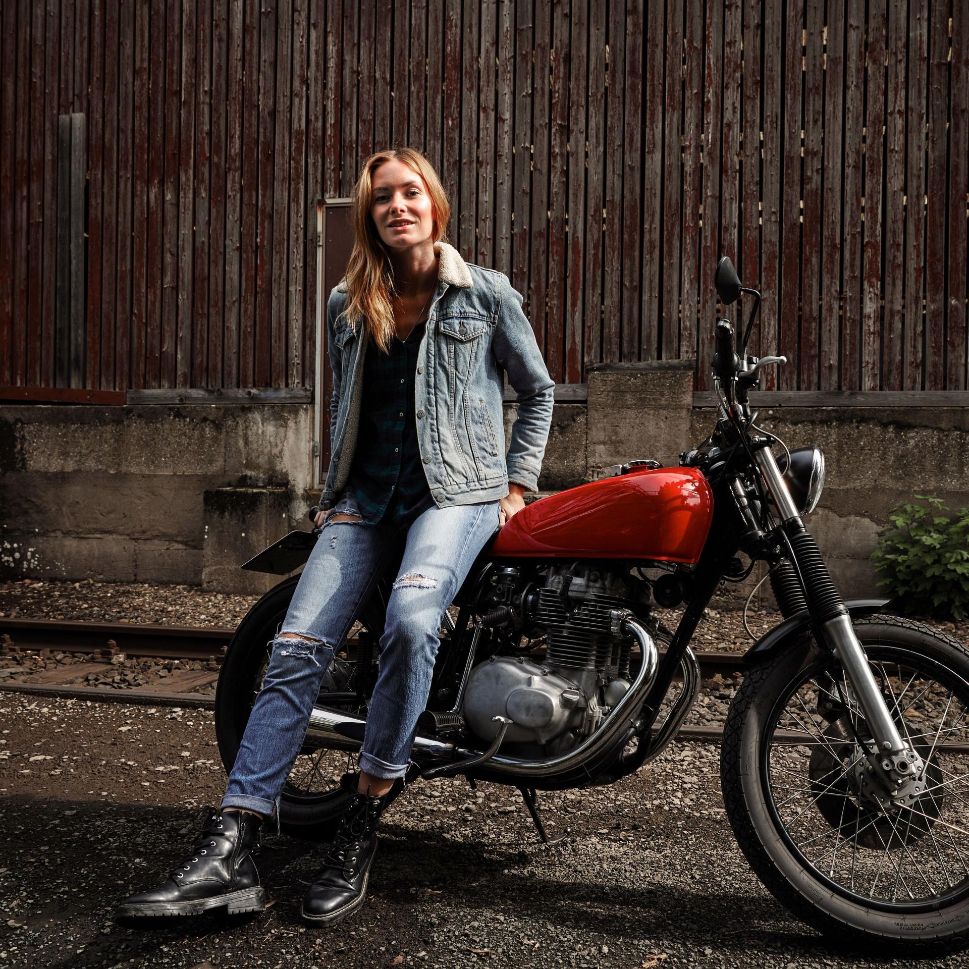 Eine junge Frau sitzt auf einem stehenden Motorrad.