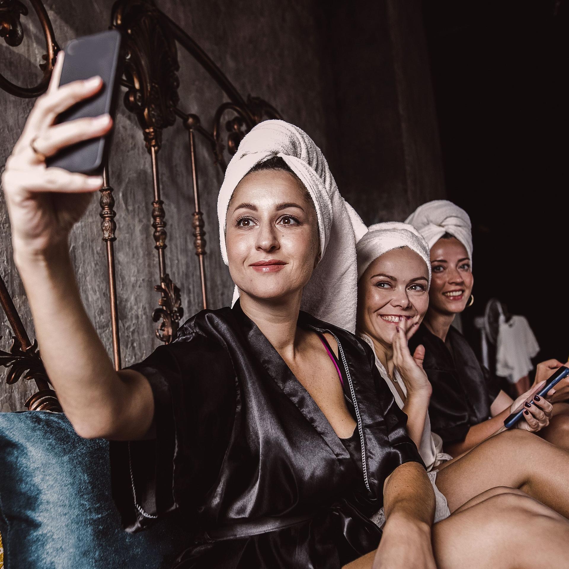 Drei Frauen in Bademänteln und Handtüchern auf dem Kopf machen ein Selfie