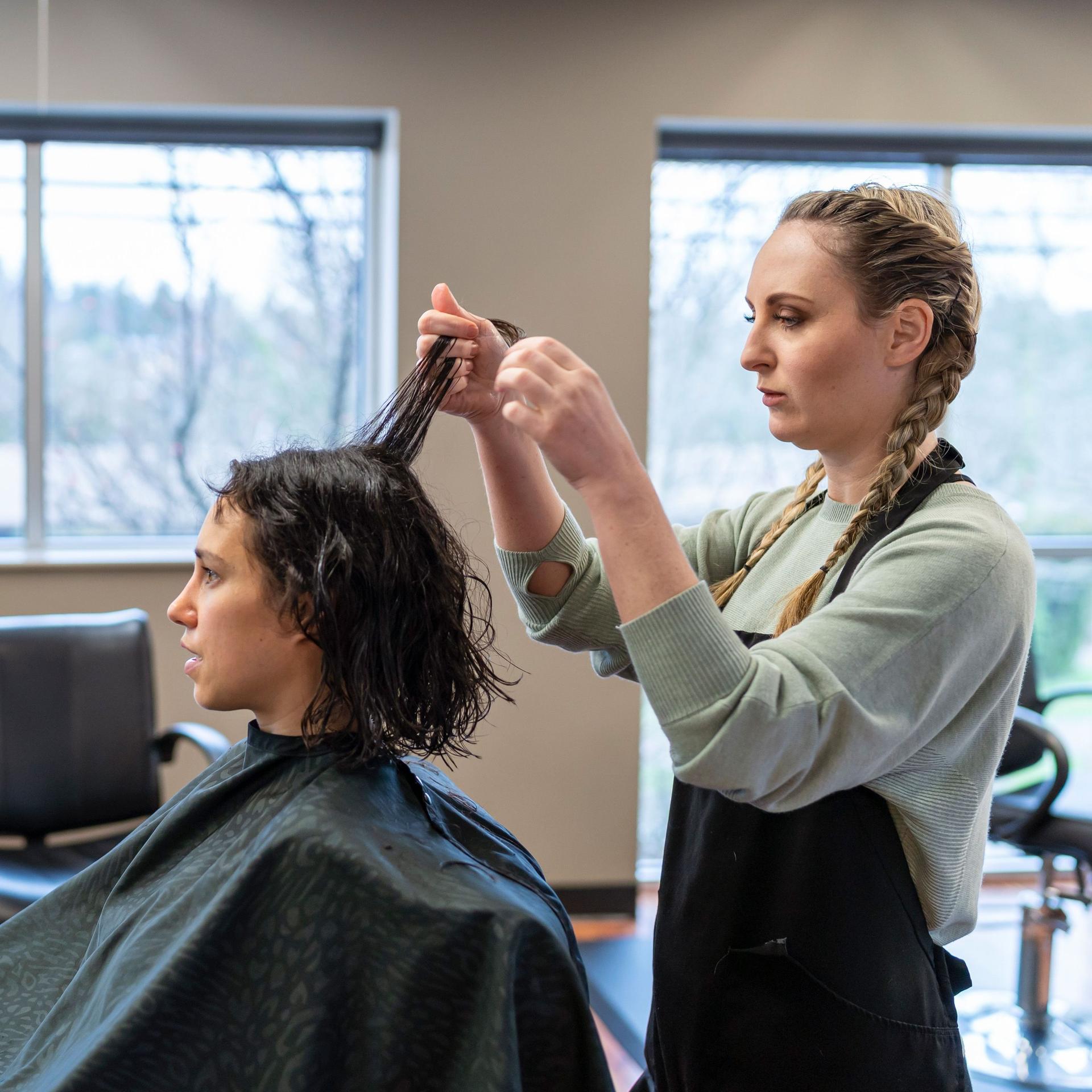 Eine Friseurin frisiert einen Kundin die Haare. 