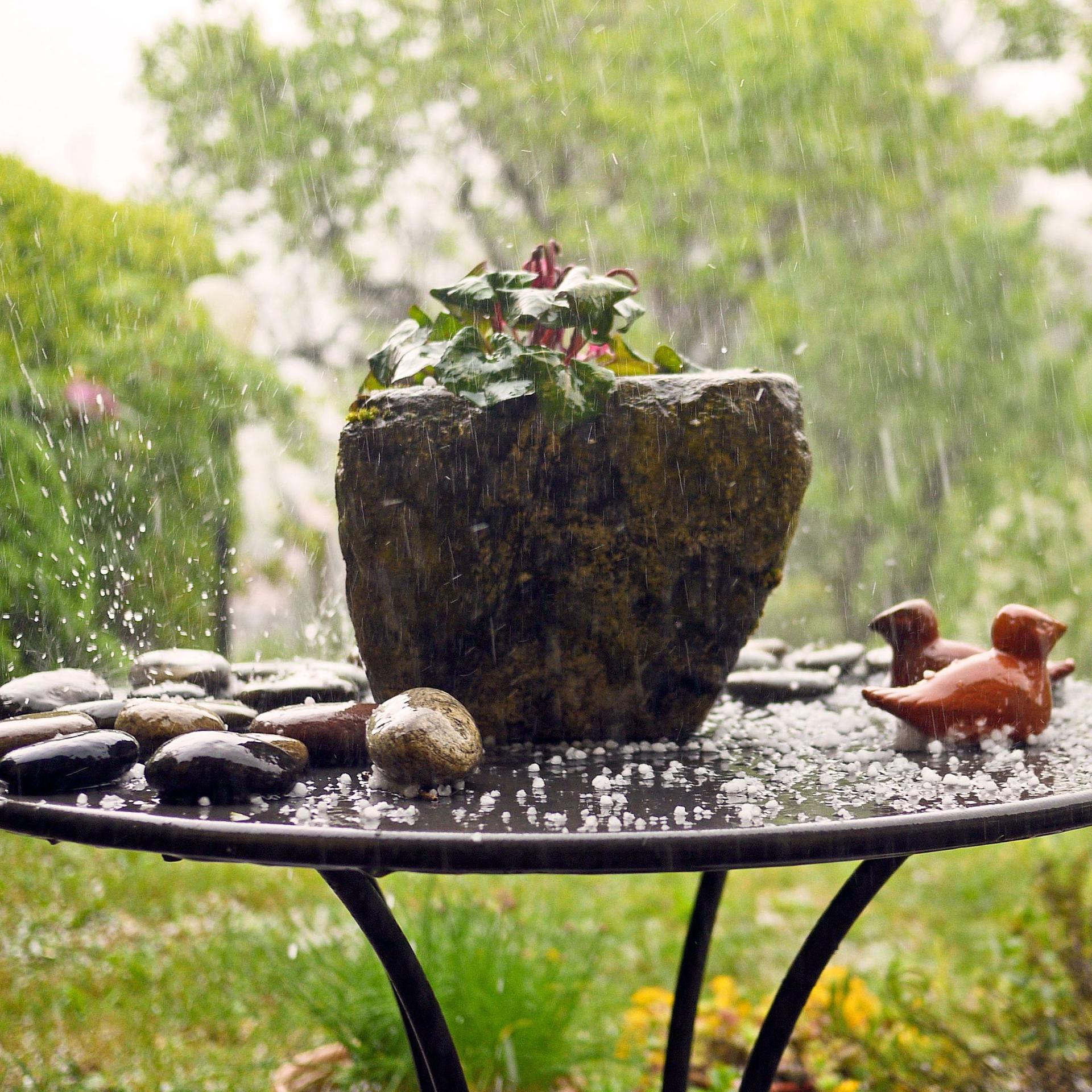 Ein Gartentisch mit Hagelkörnern. Im Hintergrund ein Garten.