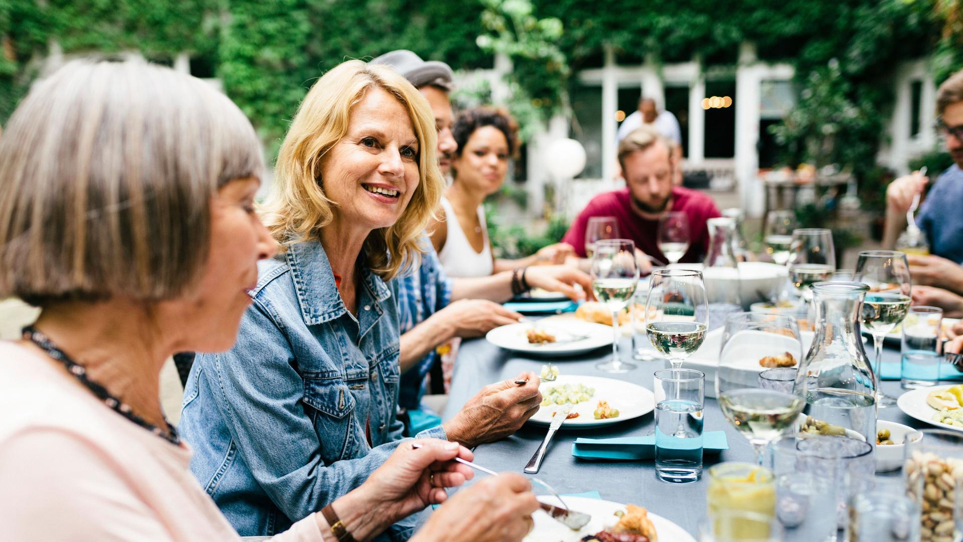 Eine Gruppe von Menschen, die gemeinsam an einem großen Tisch in einem Innenhof essen.