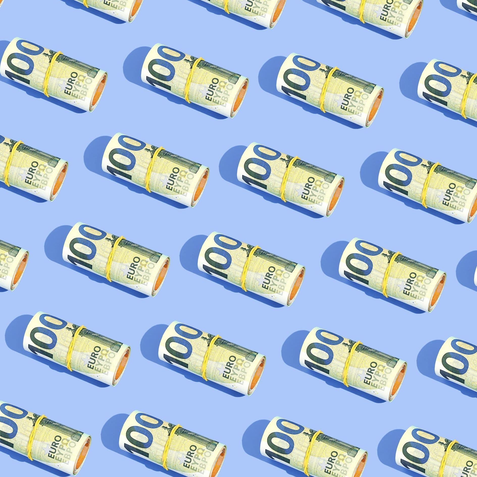 Gerollte 100-Euro-Scheine liegen auf einem blauen Hintergrund