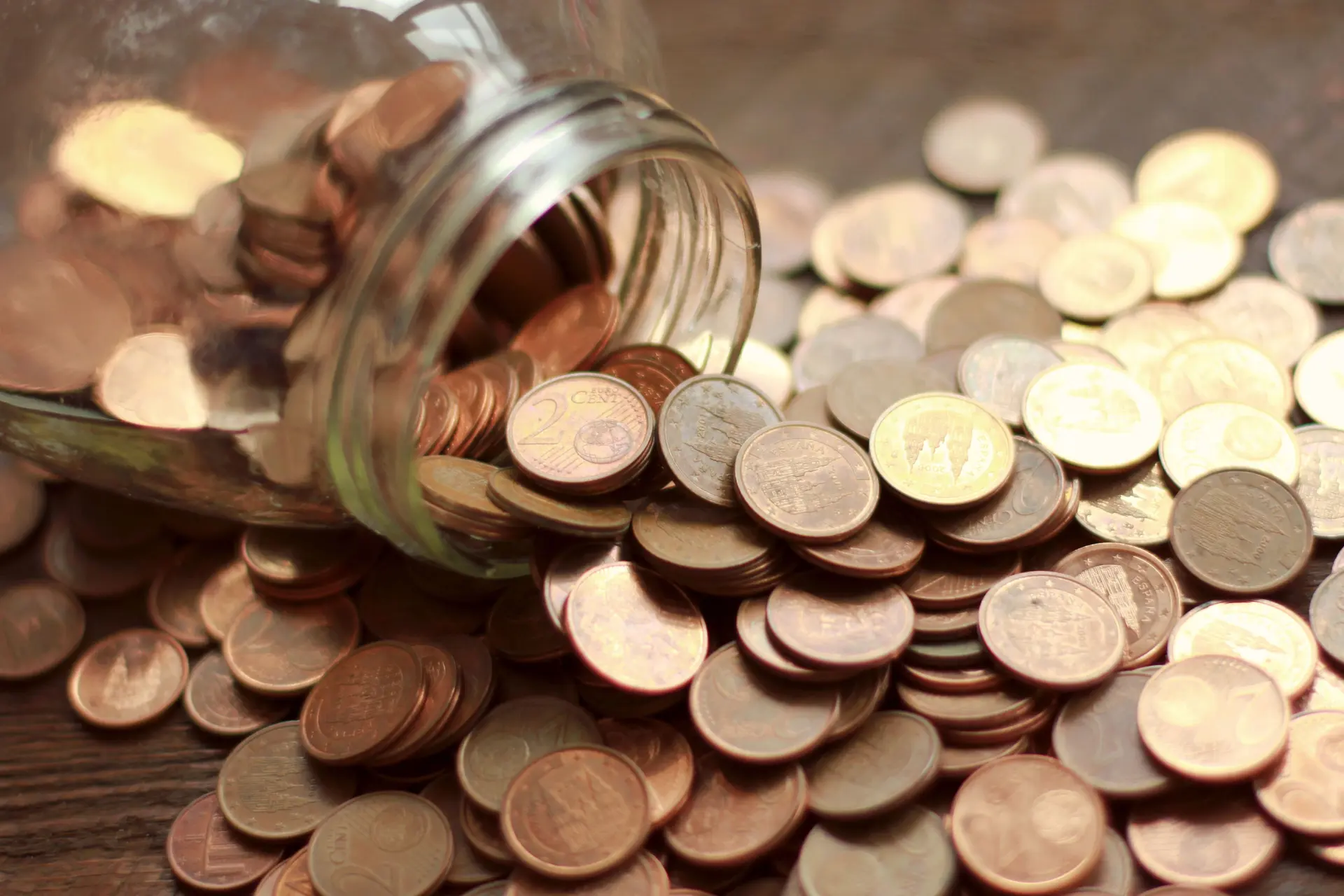 Glas mit ausgeschütteten Eurocent Münzen auf einem Tisch