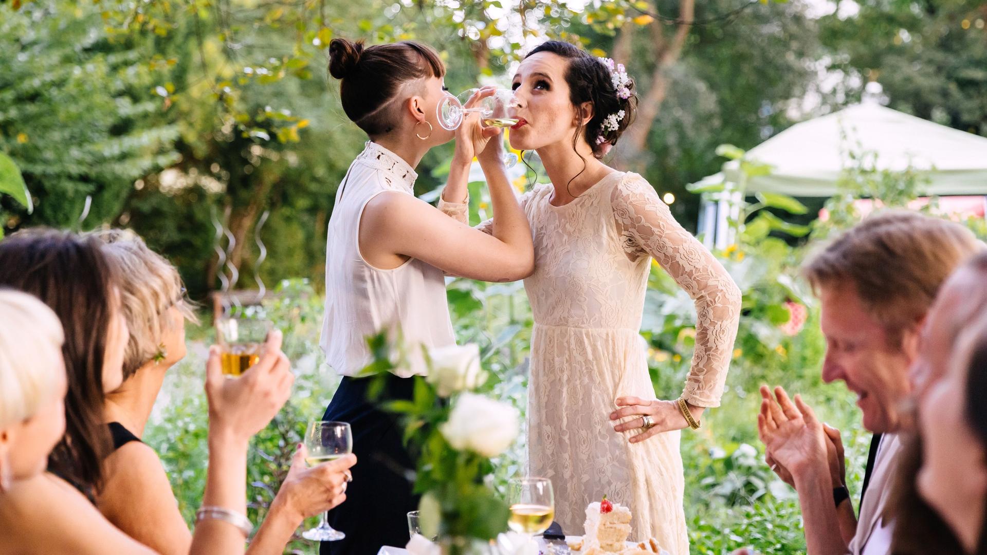 Frisch verheiratete Eheleute trinken mit Freunden auf ihre Hochzeit