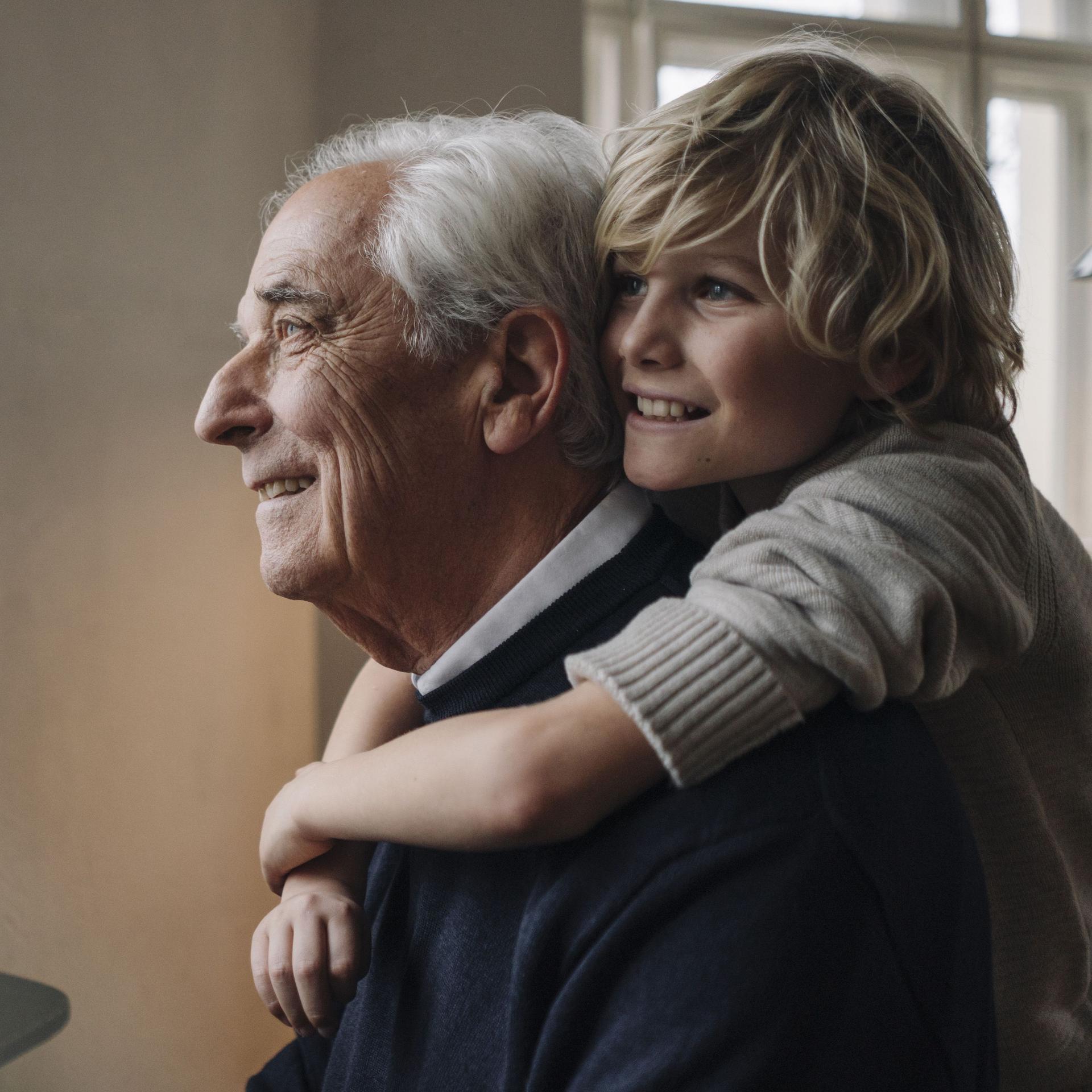 Glücklicher Enkel umarmt Großvater zu Hause