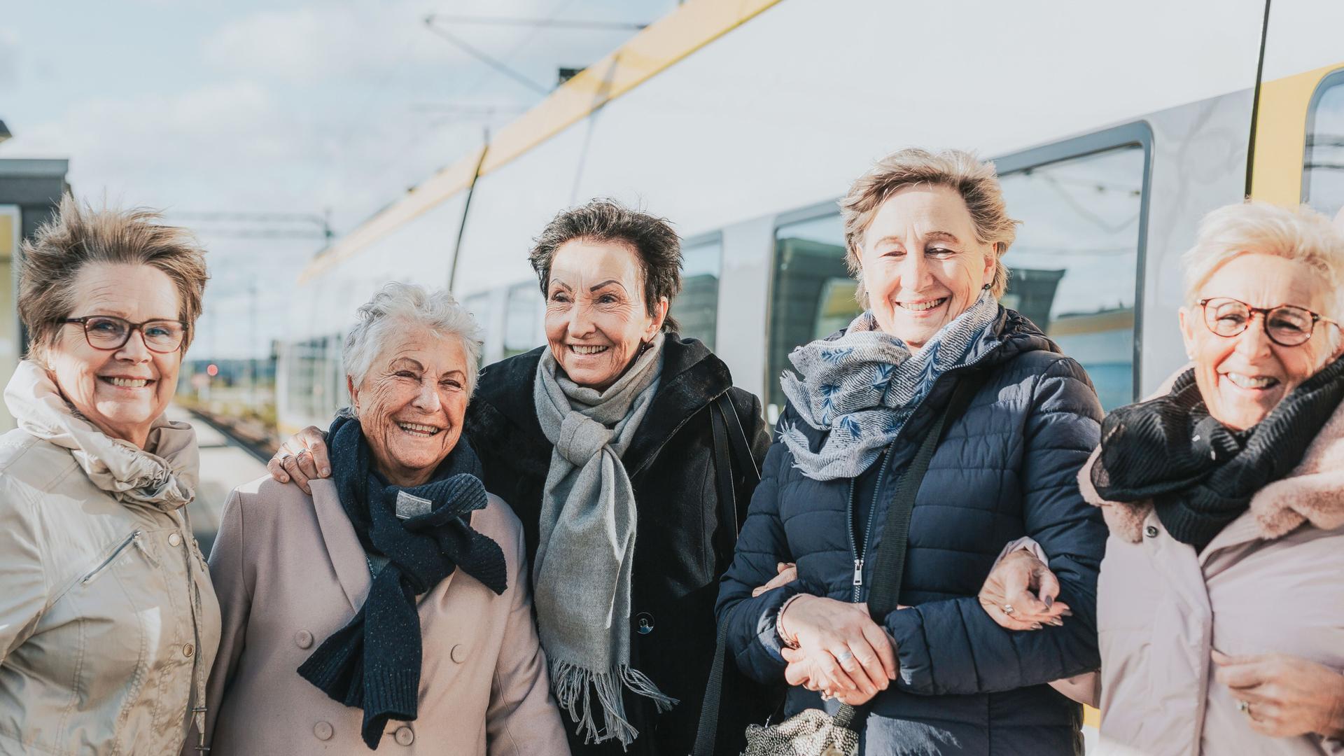 Gruppe Seniorinnen auf dem Bahnsteig vor einem Zug.