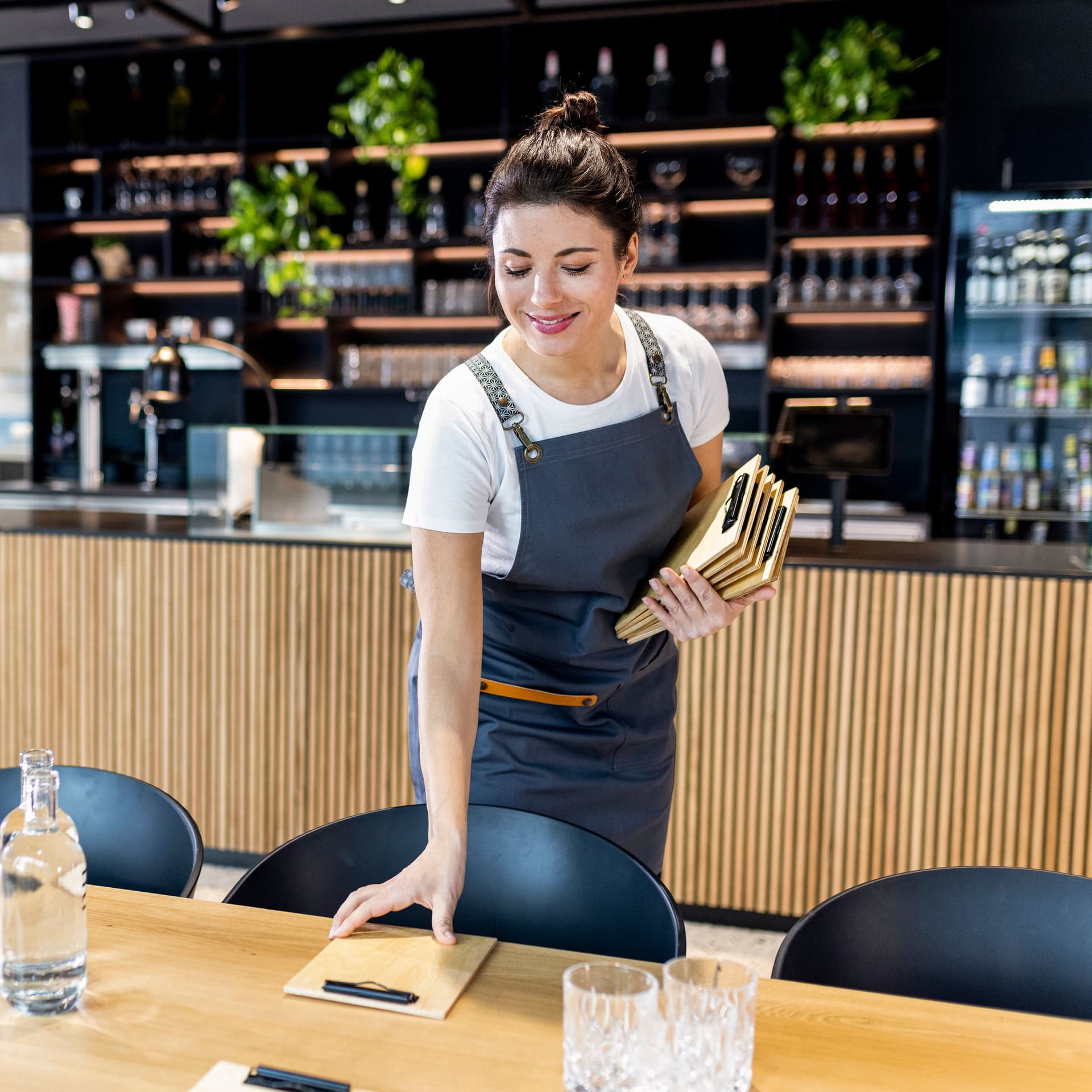 gut_gelaunte_kellnerin_deckt_tisch_im_restaurant_fuer_geschäftstreffen_GI-1365252302-4493