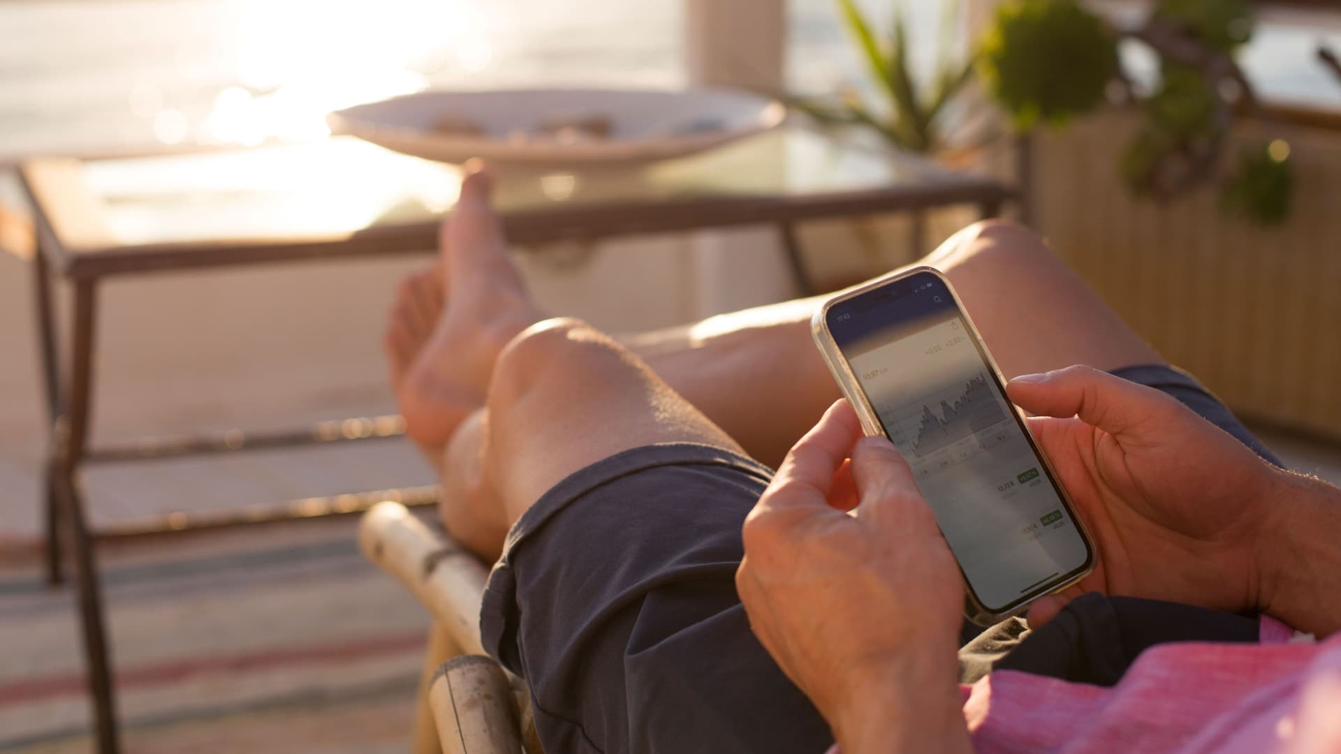 Anlagemöglichkeiten Ein Mann schaut auf sein Mobiltelefon und verfolgt Wertpapierkurse