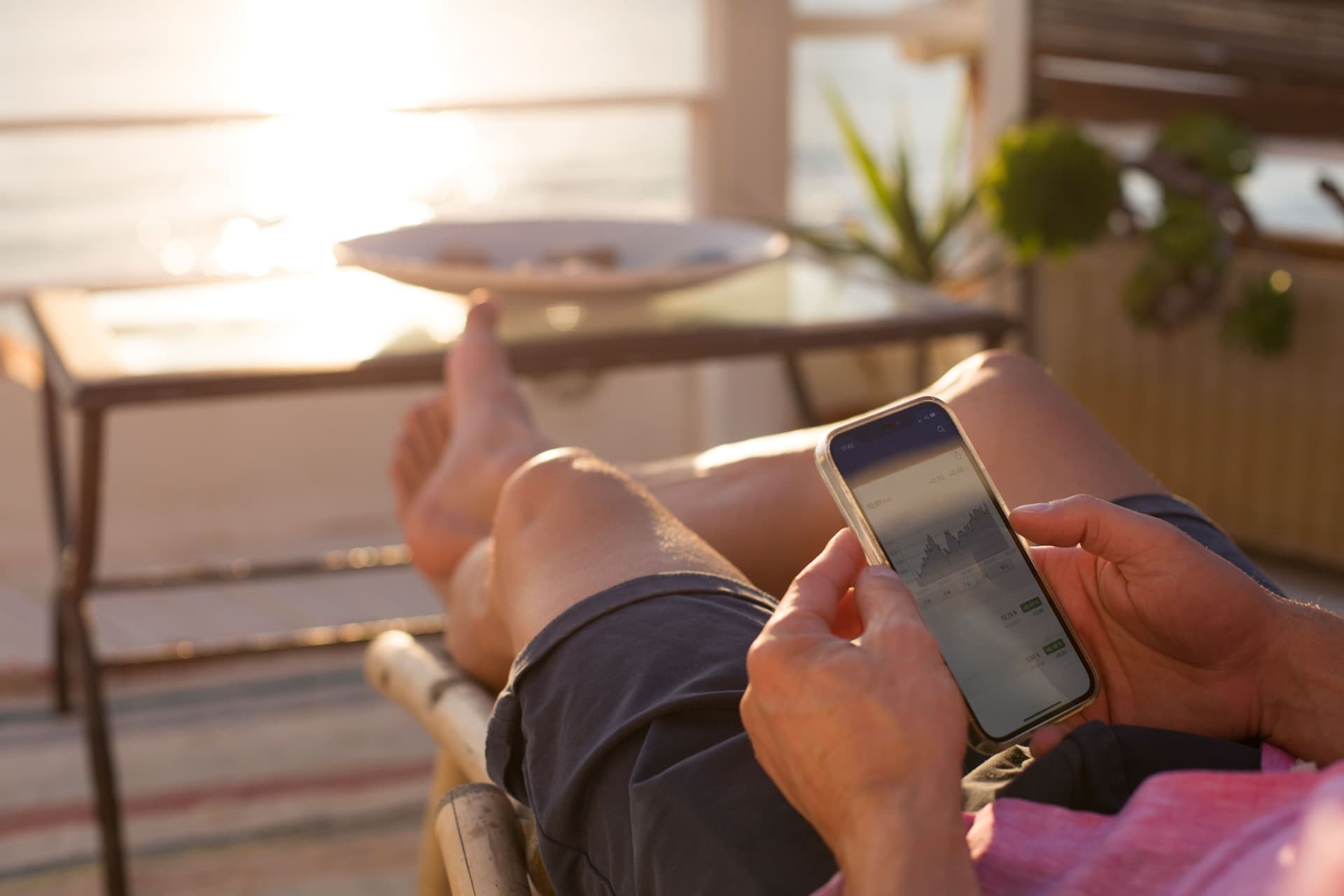 Hände halten ein Mobiltelefon in der Abendsonne