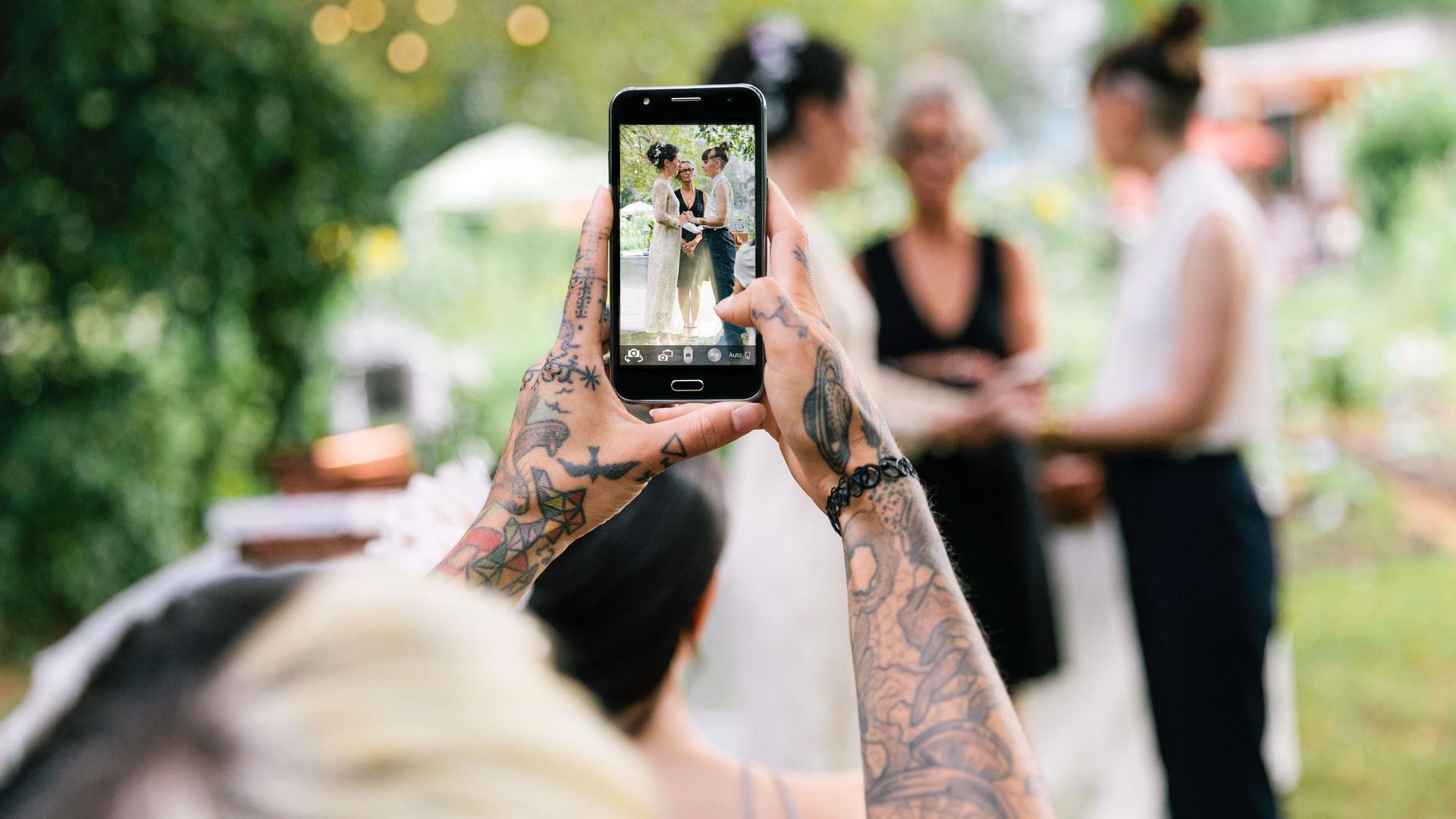 Tätowierte Frau macht ein Hochzeitsfoto mit dem Smartphone