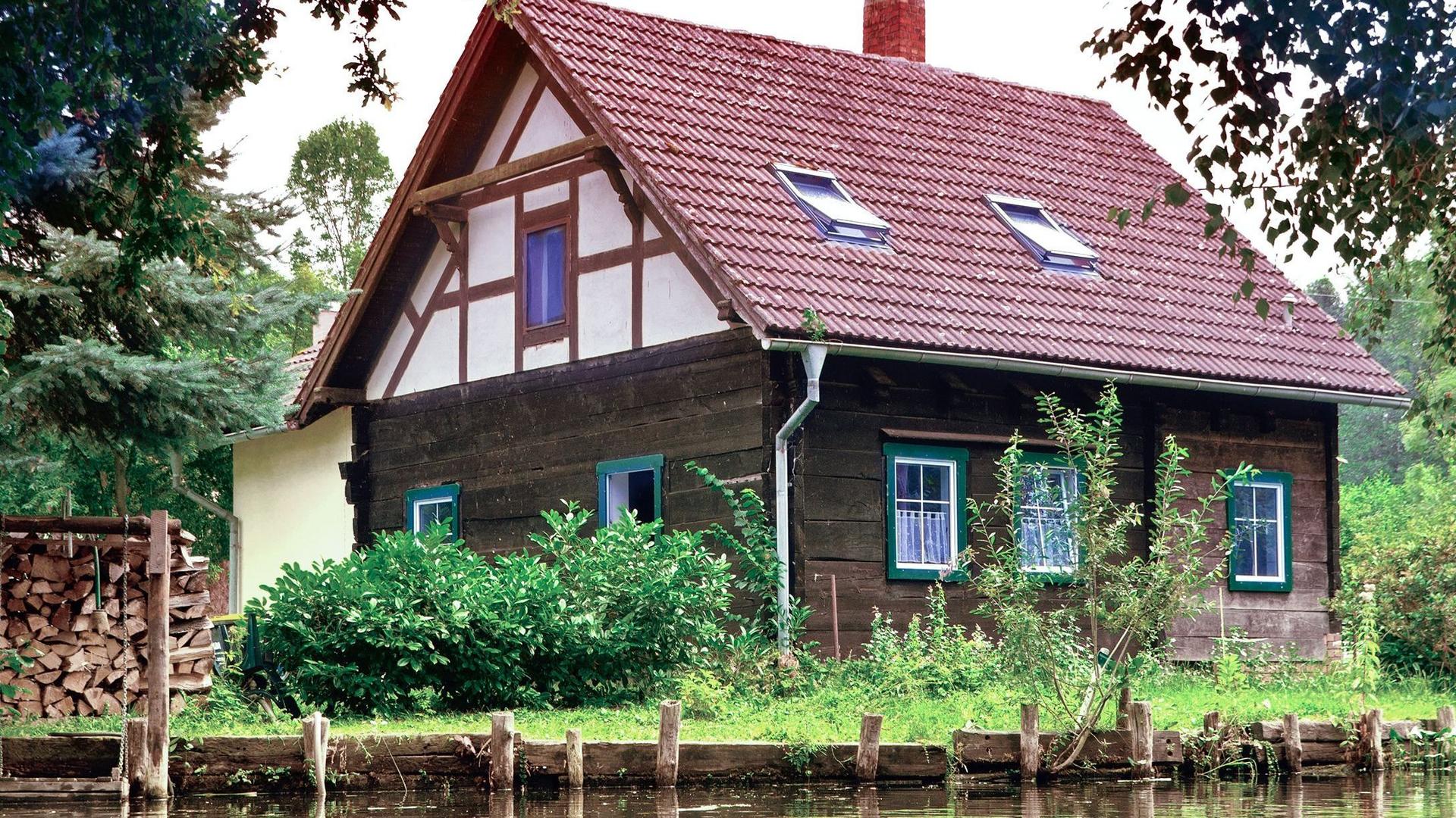 Ein Fachwerkhaus an einem Flußufer im Spreewald.