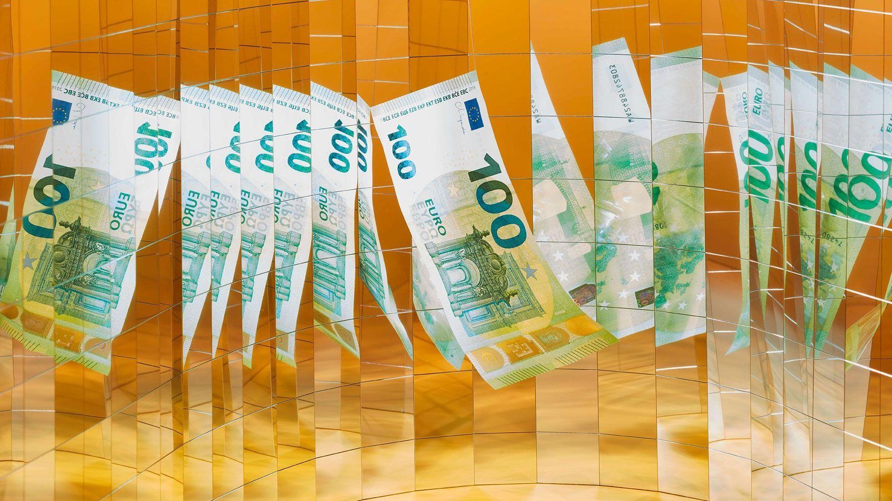 Inszeniertes Stillleben mit einem 100 Euro Schein. Durch eine Vielzahl von kleinen Spiegeln, die im Halbkreis angeordnet sind, sieht man die Banknote vielfach gespiegelt. Die Geldmittel steht auf einem goldenen Untergrund.