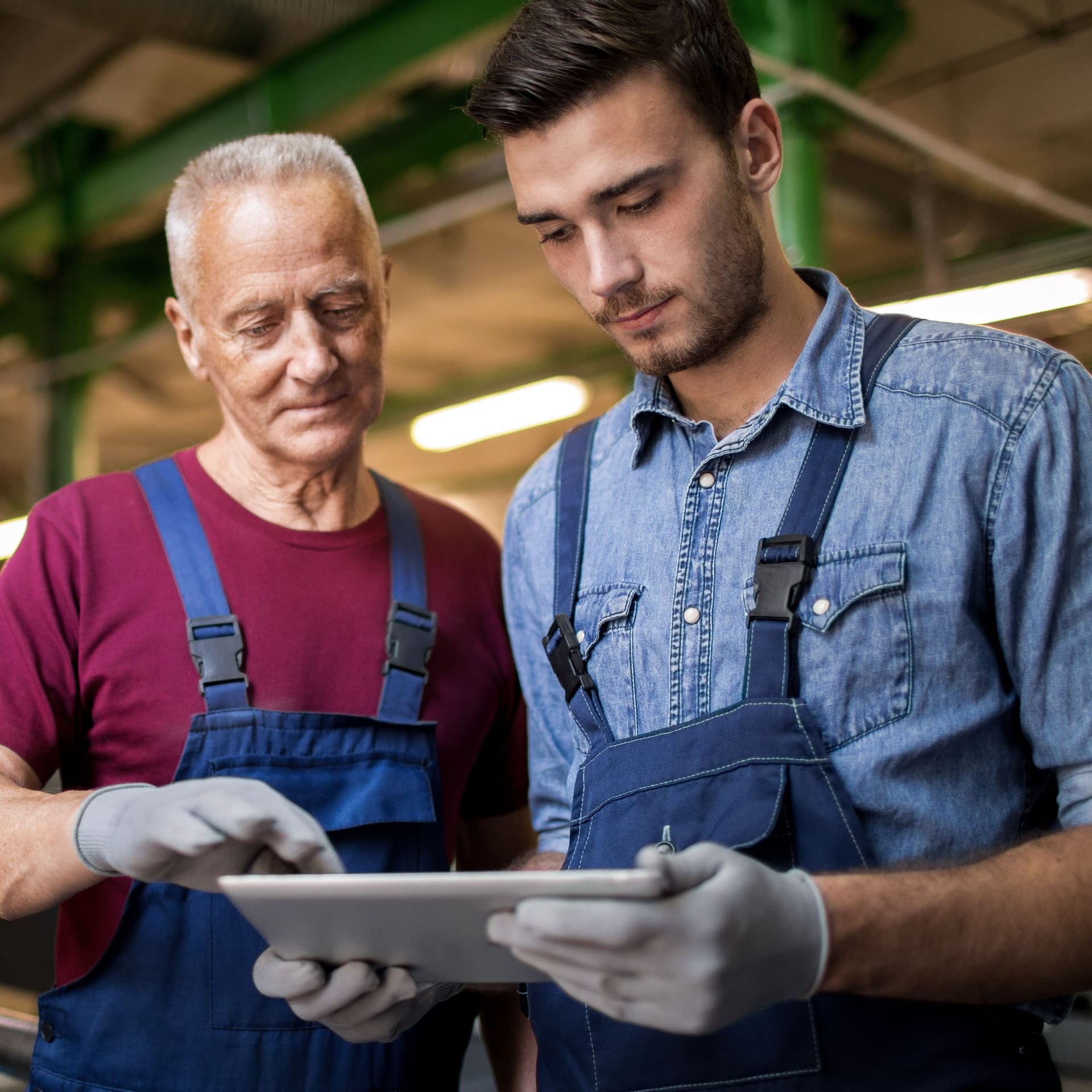 Zwei Männer in einer Fabrik, die auf ein Tablet schauen.