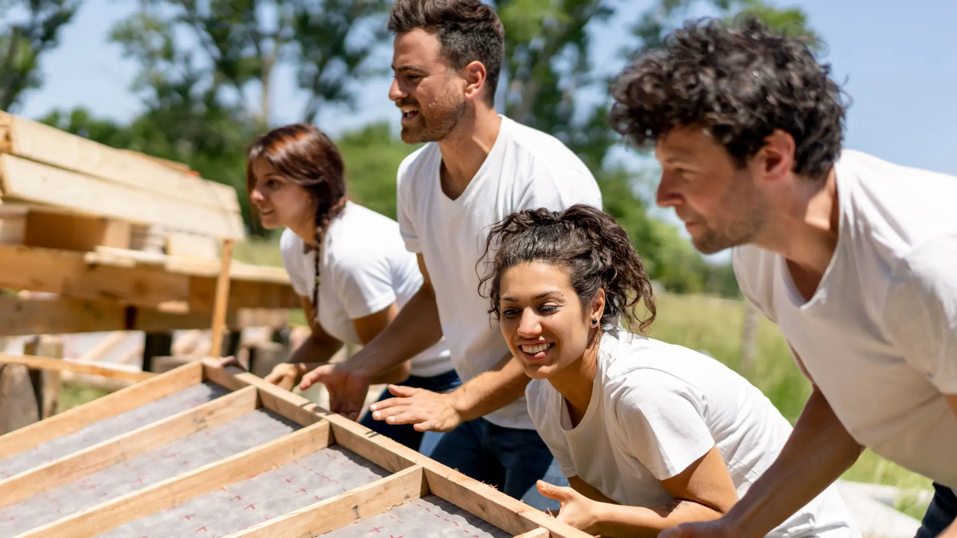 Junge Leute arbeiten an einem wohltätigen Bauprojekt. Sie arbeiten in der Sonne mit Holz.