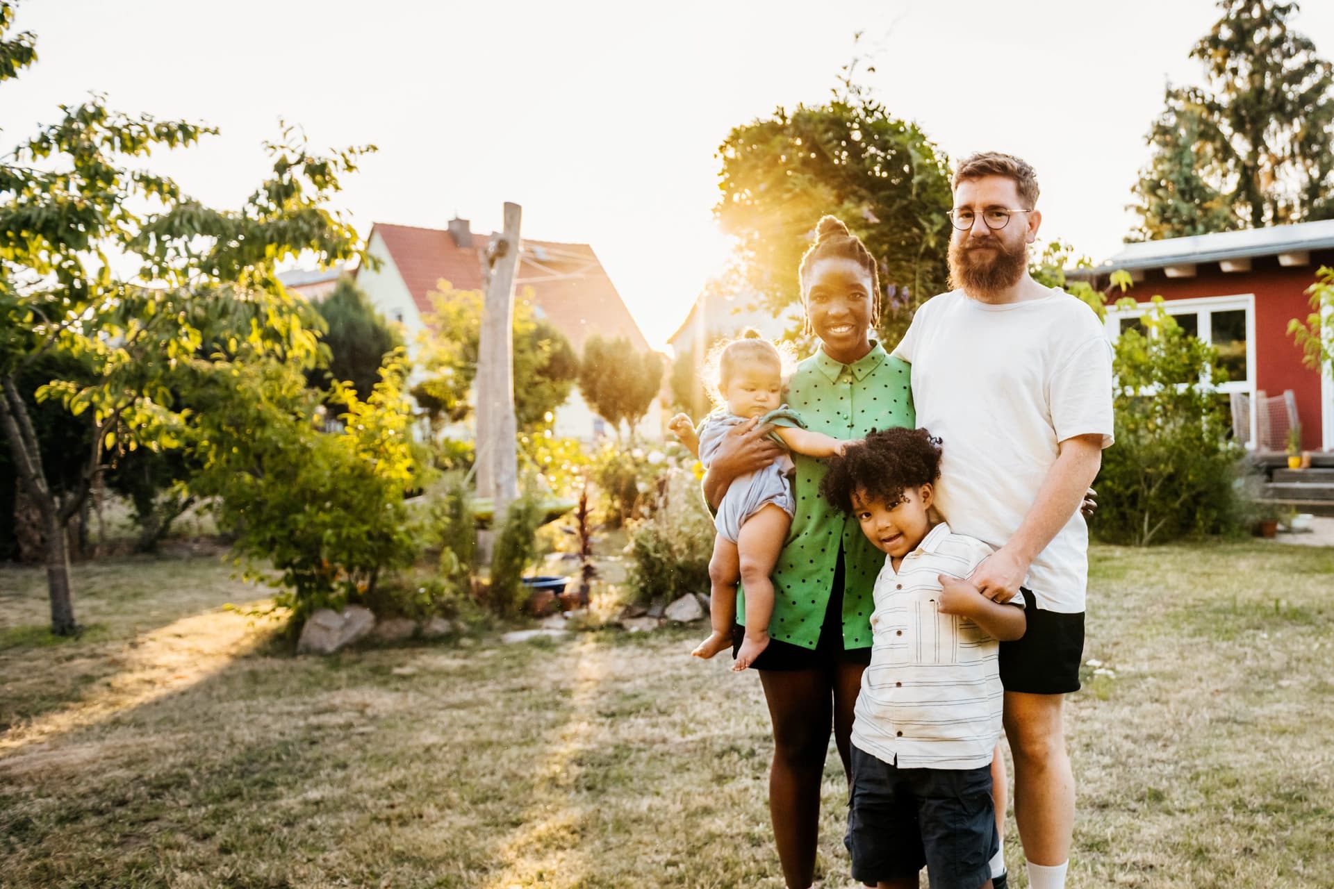 Portrait einer jungen Familie im Garten eines Einfamilienhauses.