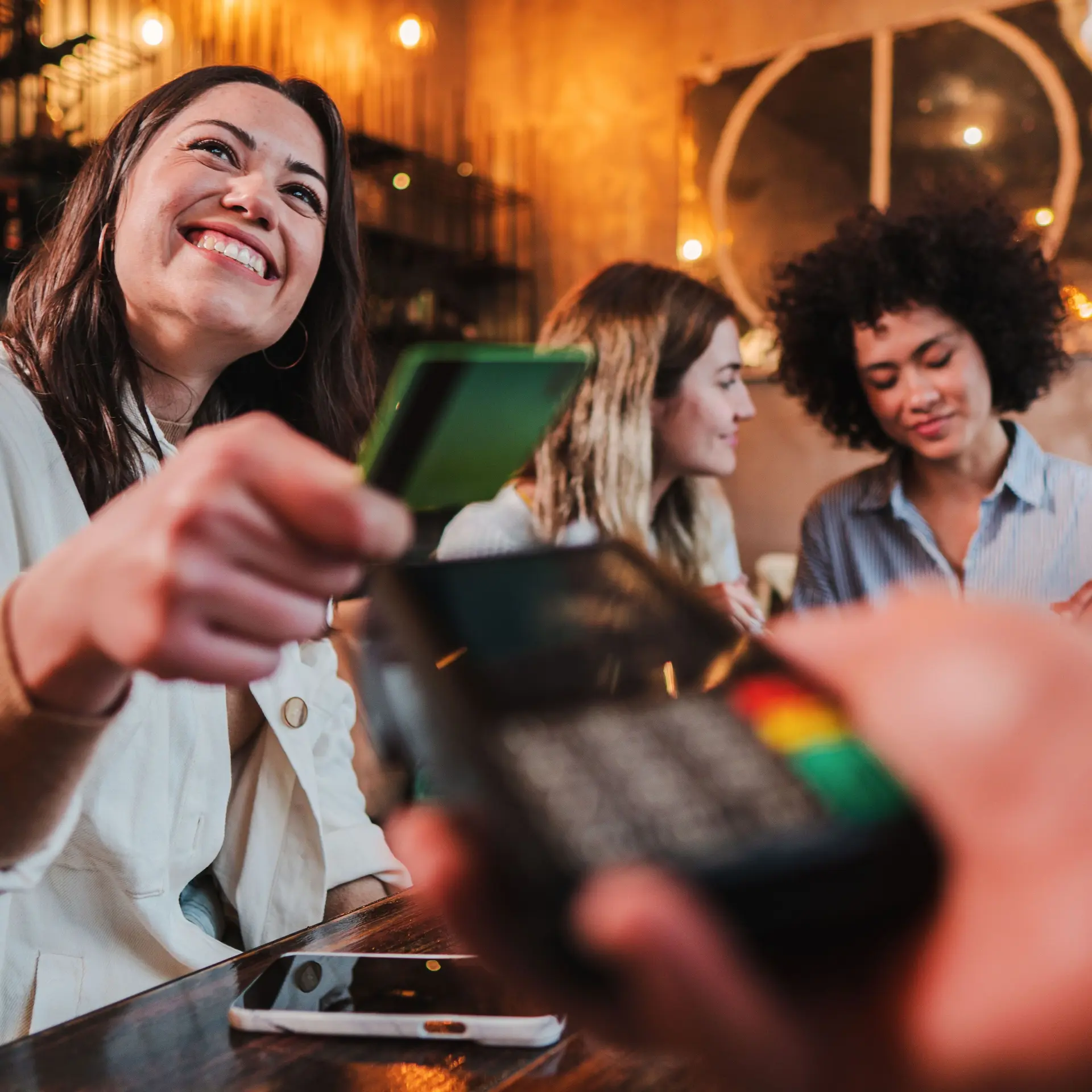 Eine junge Frau bezahlt in einem Restaurant mit einer Karte