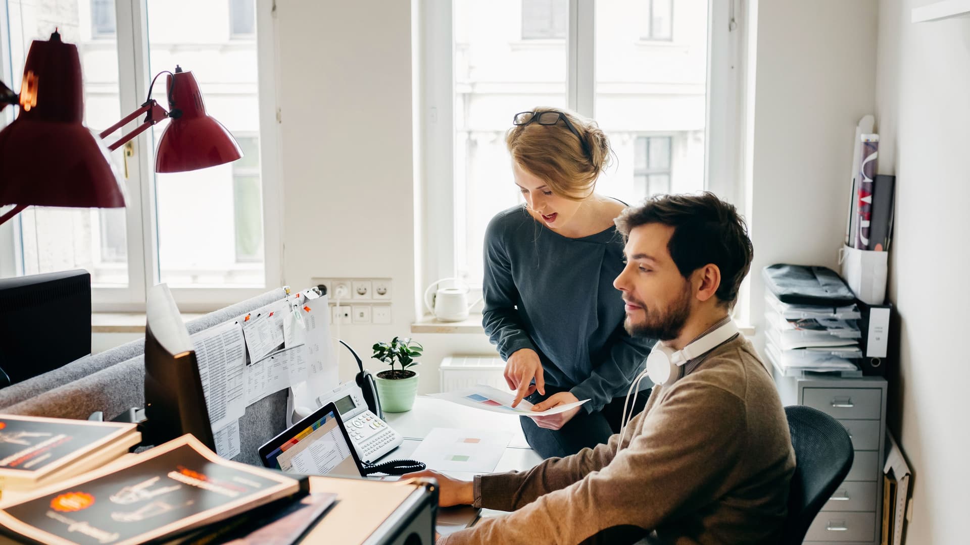 Ein Mann und eine Frau sitzen gemeinsam in einem Büro vor dem Computer und planen.