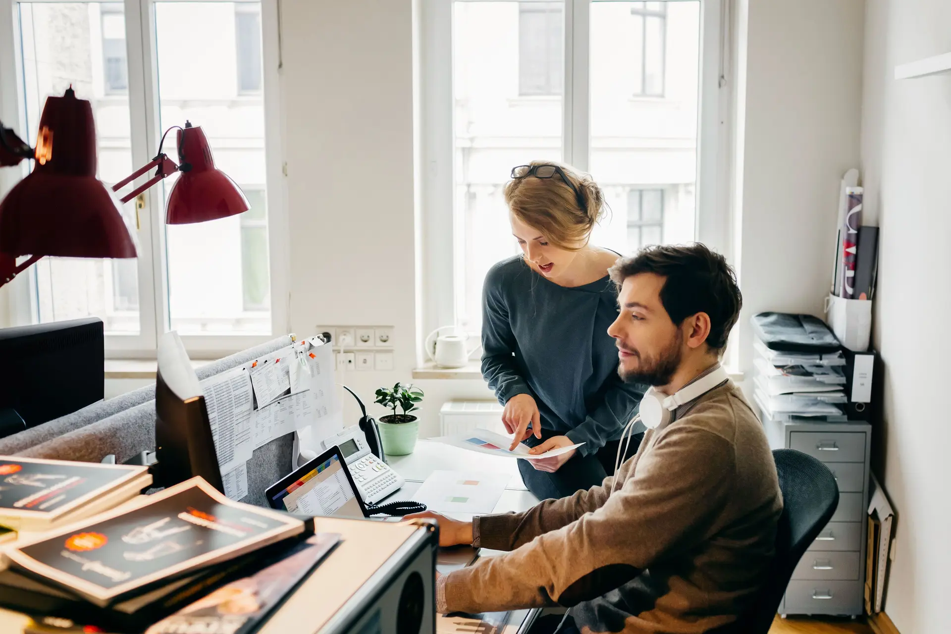 Ein Mann und eine Frau sitzen gemeinsam in einem Büro vor dem Computer und planen.