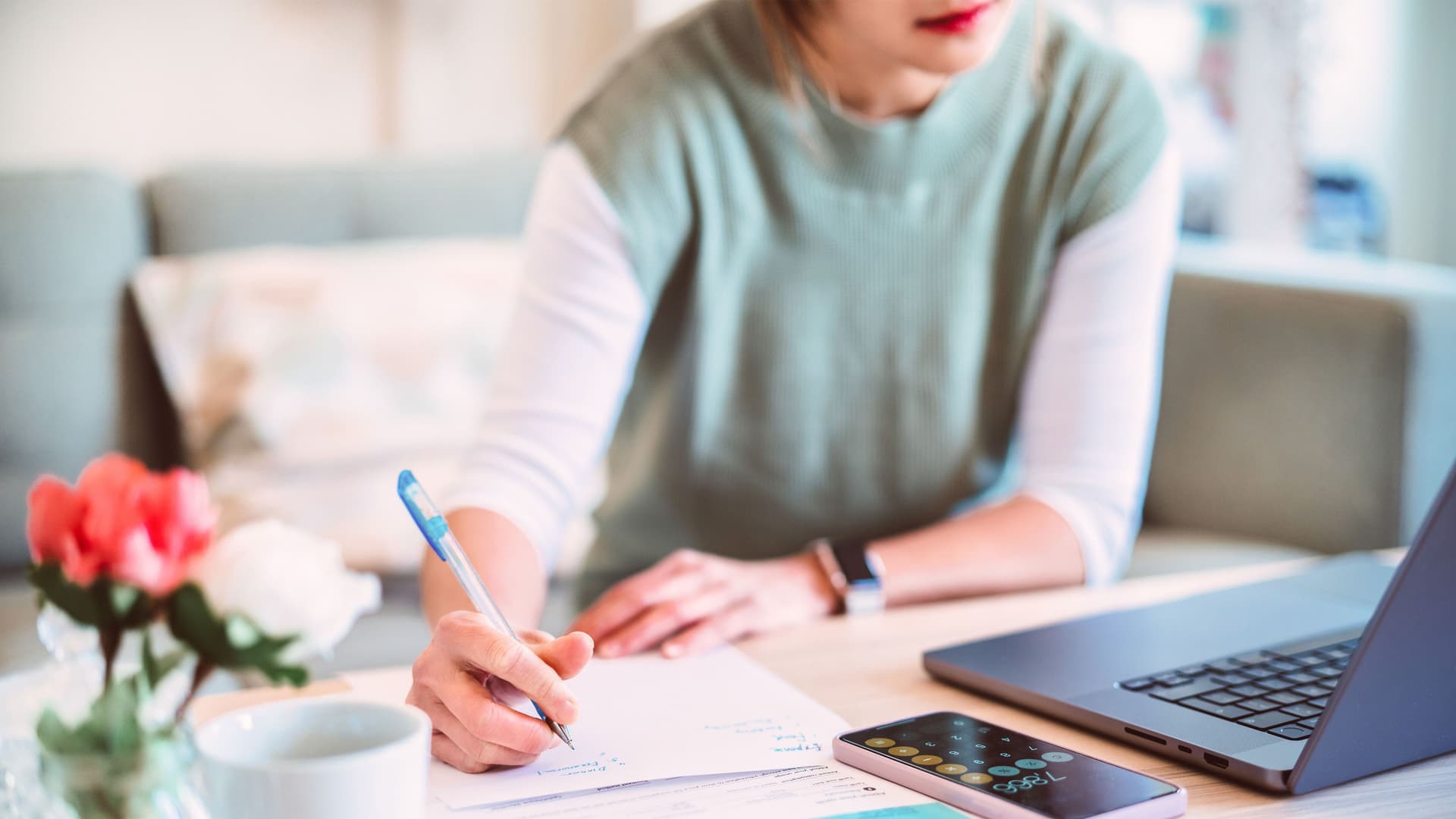 Junge Frau verwaltet Hausfinanzierung per Laptop und Smartphone