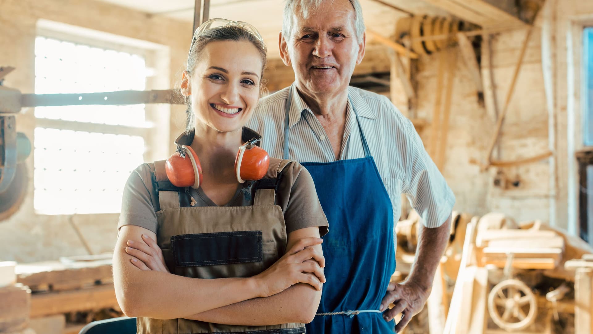 Älterer Schreiner mit junger Schreinerin in der Holzwerkstatt