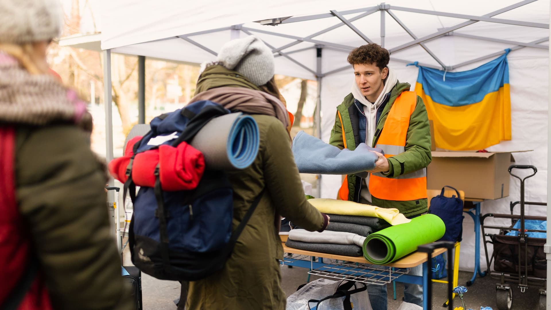 Freiwilliger verteilt Decken und andere Spenden an ukrainische Flüchtlinge in einen Zelt.