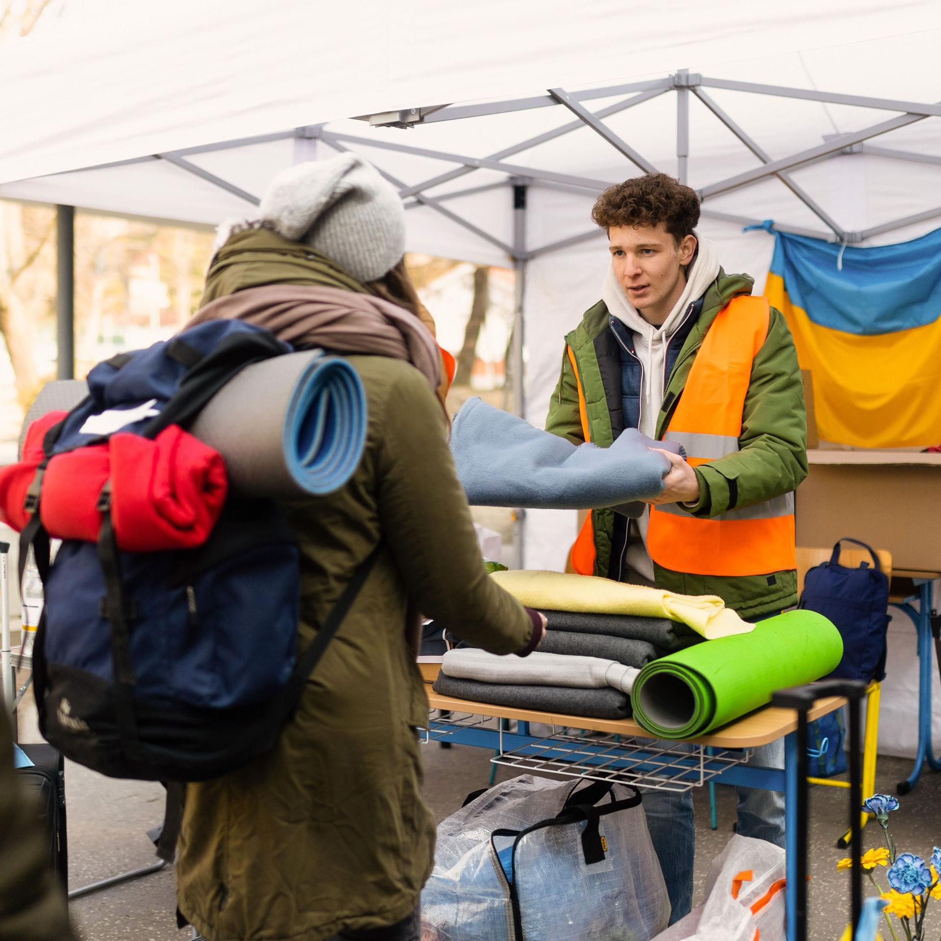 Freiwilliger verteilt Decken und andere Spenden an ukrainische Flüchtlinge in einen Zelt.
