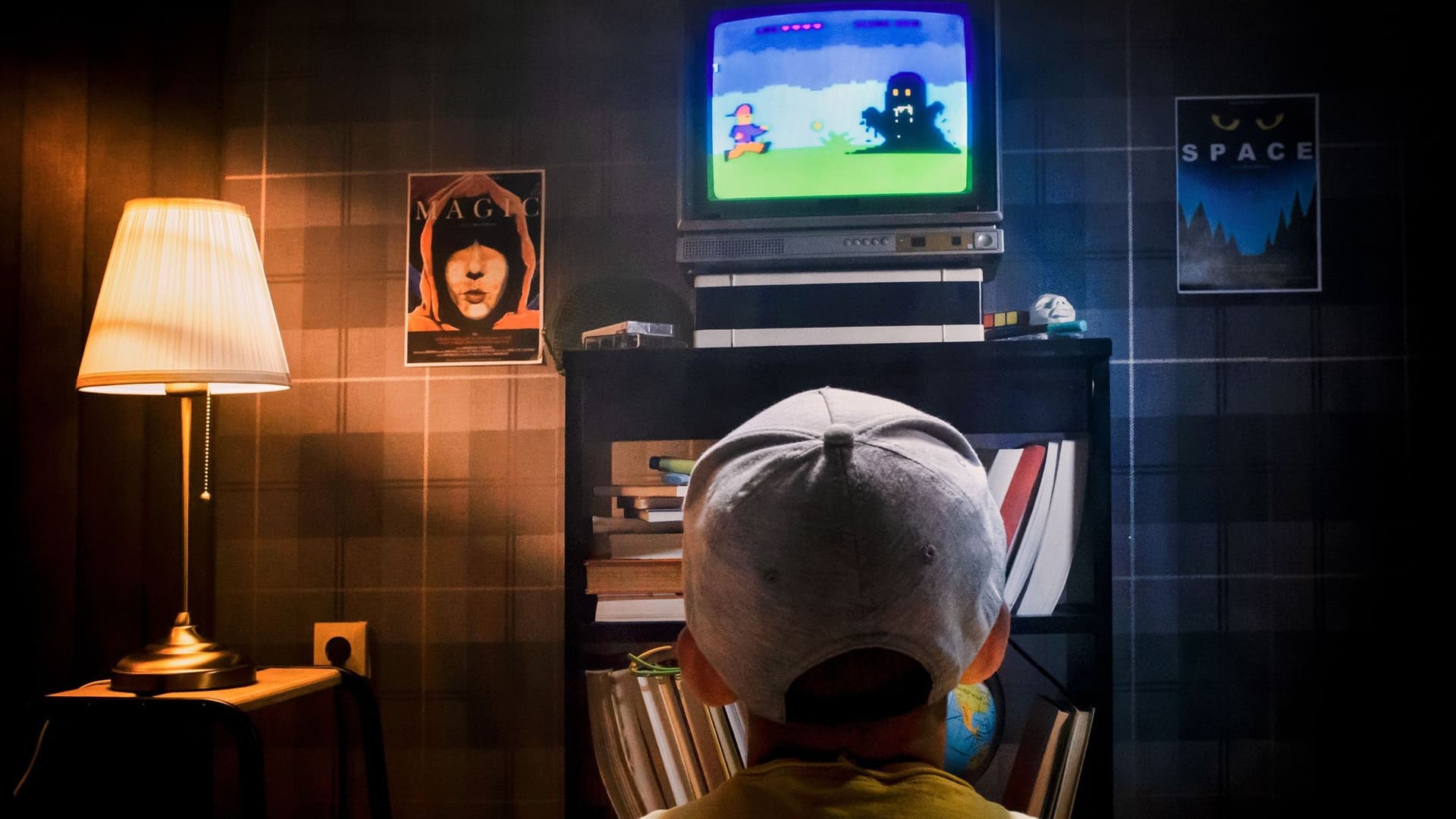 Foto eines Kindes vorm Fernseher. Auf dem Fernseher läuft ein Konsolenspiel. Das Foto ist in den 80er Jahren aufgenommen.