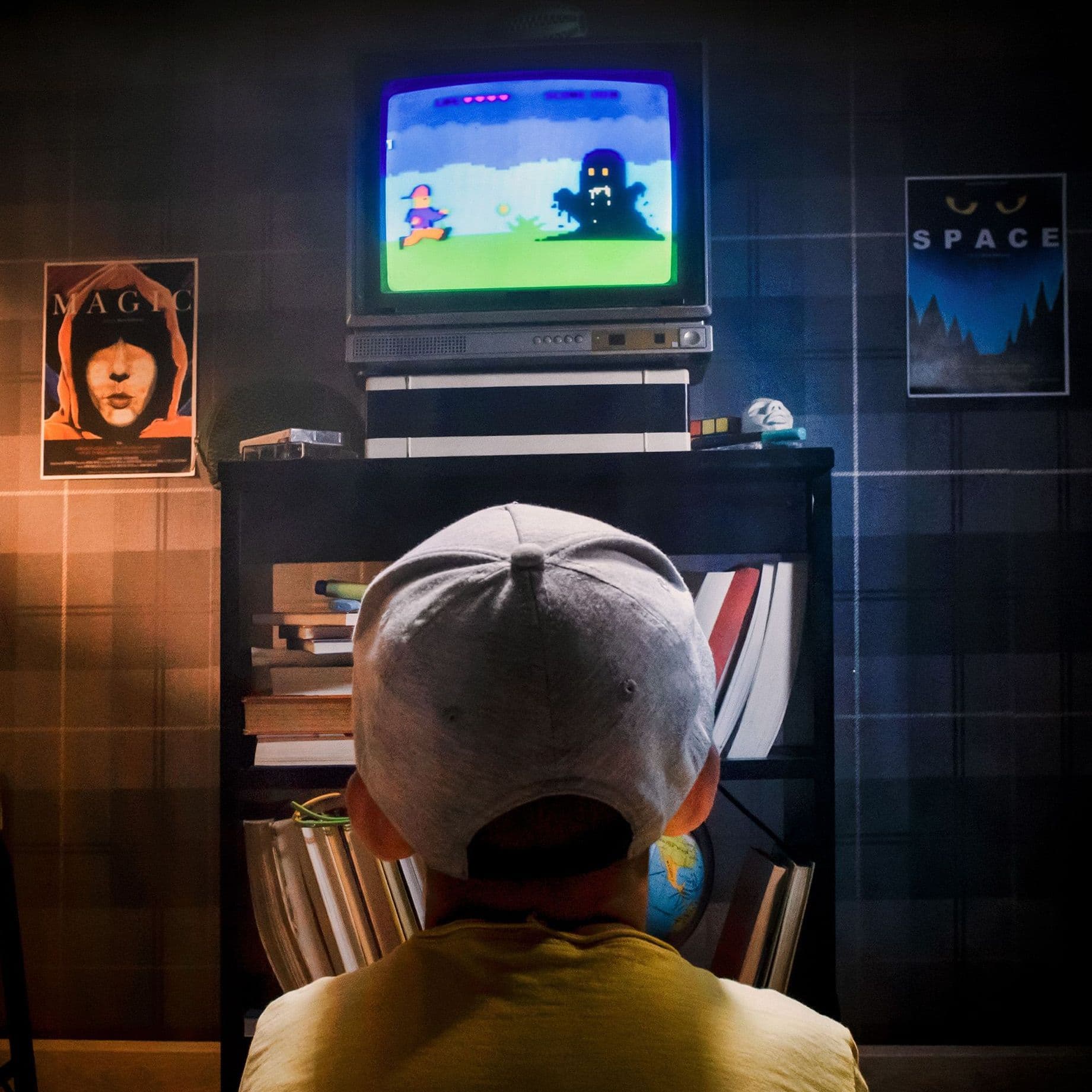 Foto eines Kindes vorm Fernseher. Auf dem Fernseher läuft ein Konsolenspiel. Das Foto ist in den 80er Jahren aufgenommen.