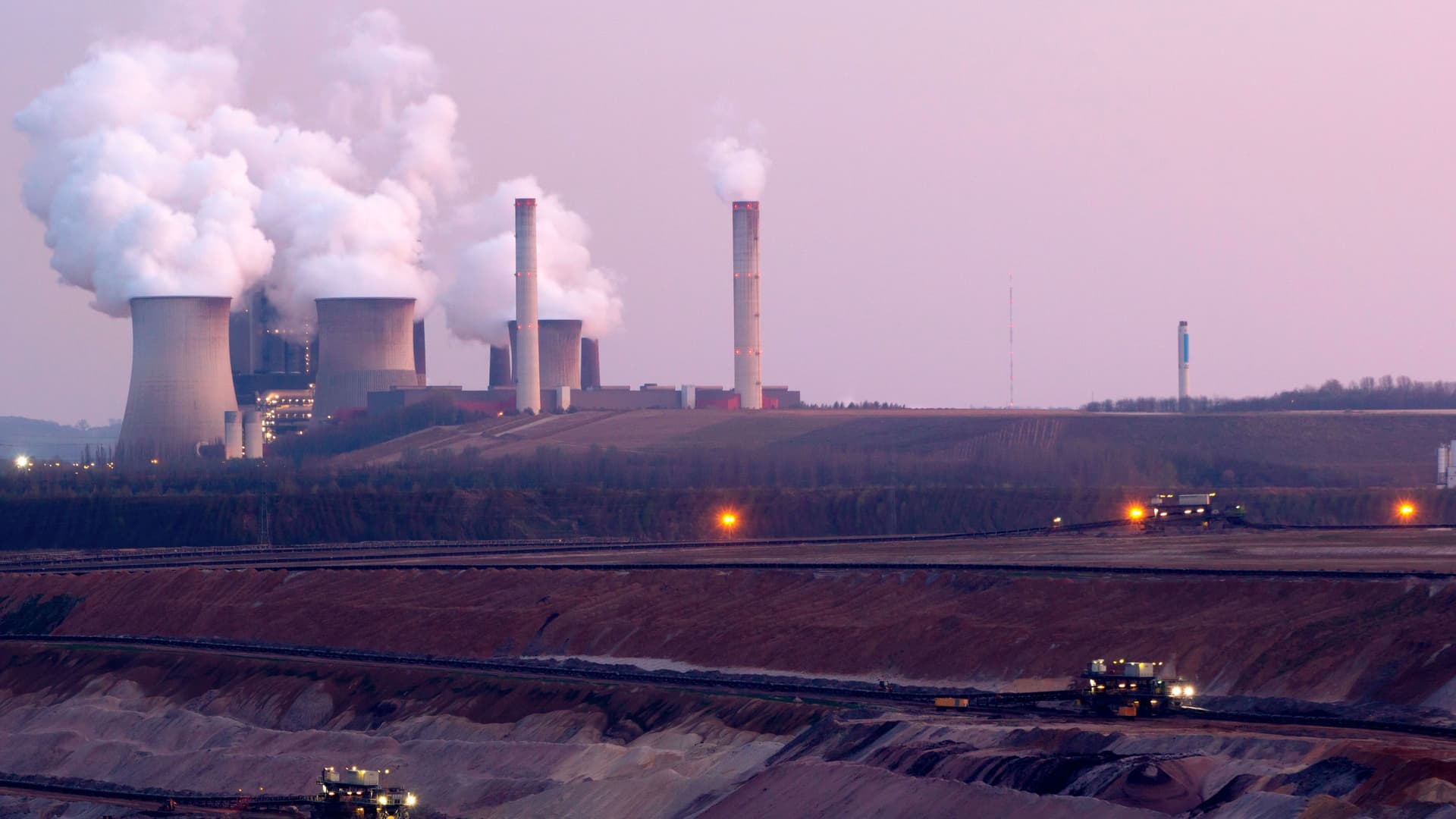 Darum ist Green Growth für Unternehmen wichtig Kohlebergbau-Grube mit Baggern in einer Abendstimmung. Im Hintergrund ist ein Kraftwerk mit dampfenden Schloten zu sehen.