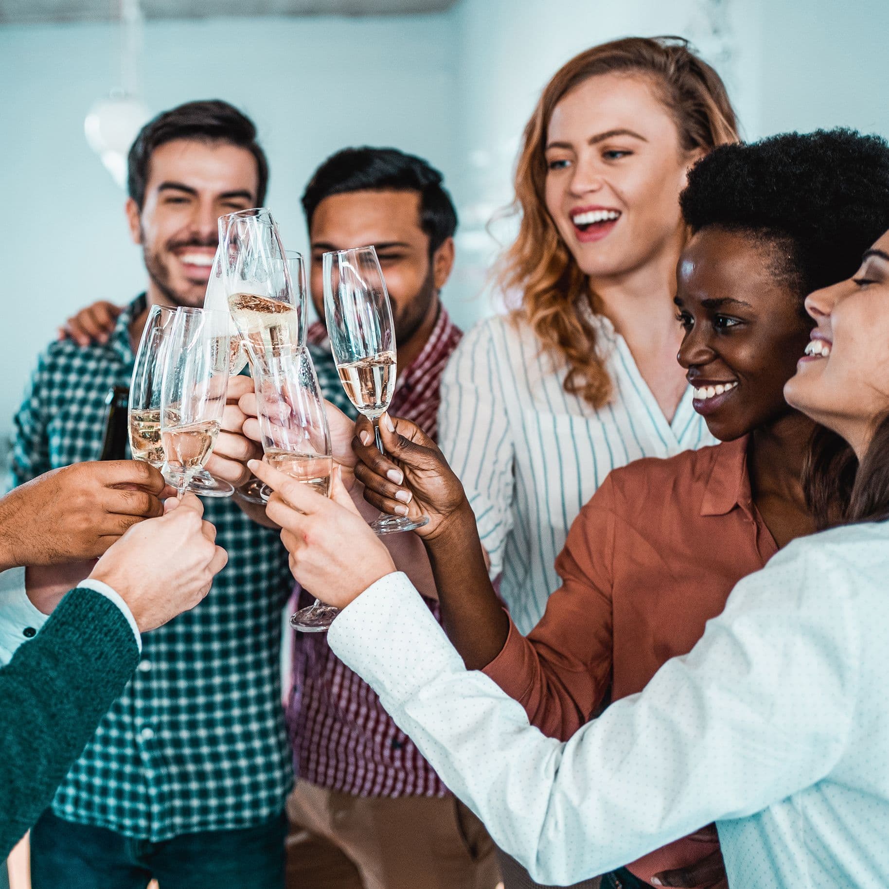 Kollegen feiern in einem Büro. Sie stoßen mit Sekt an.